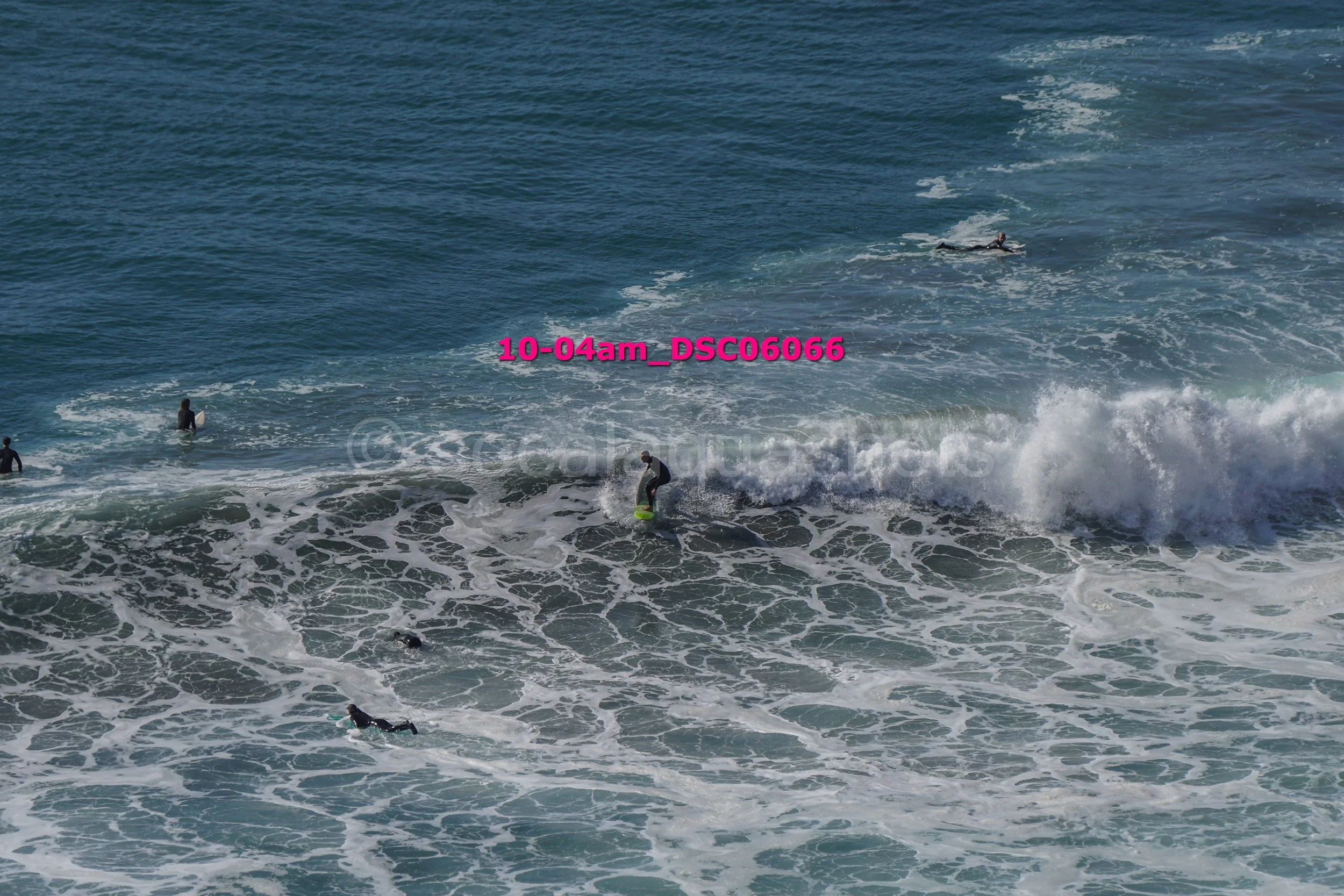 People surfing and swimming in the ocean with waves and foam, daytime