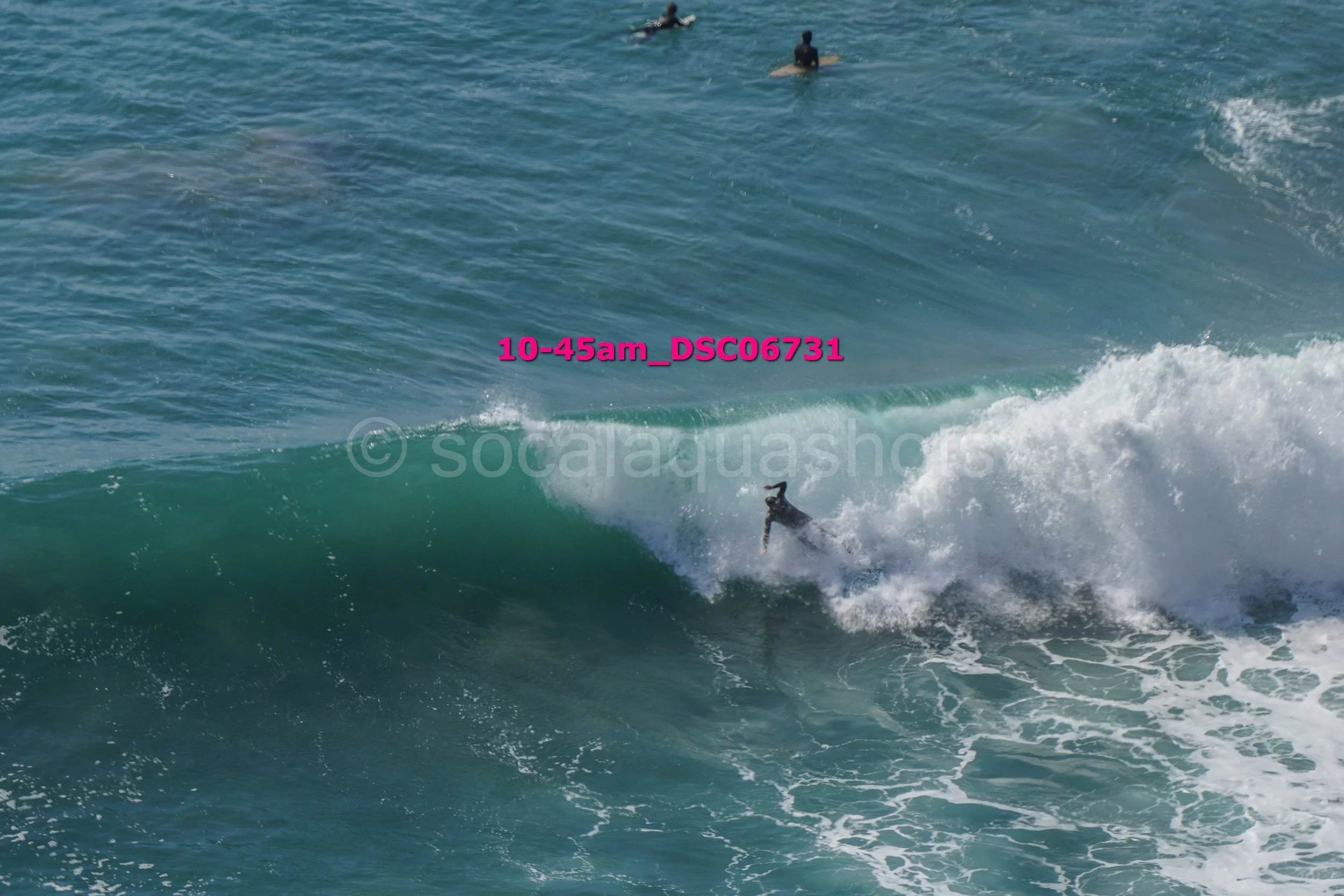 Surfer riding a large wave in the ocean with three other surfers in the background