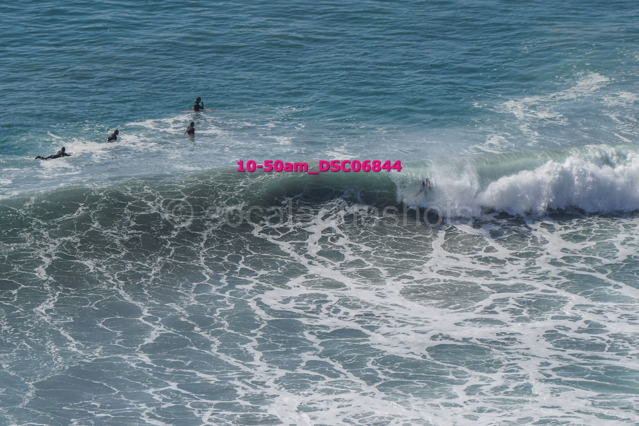 Surfers riding and waiting for waves in the ocean.