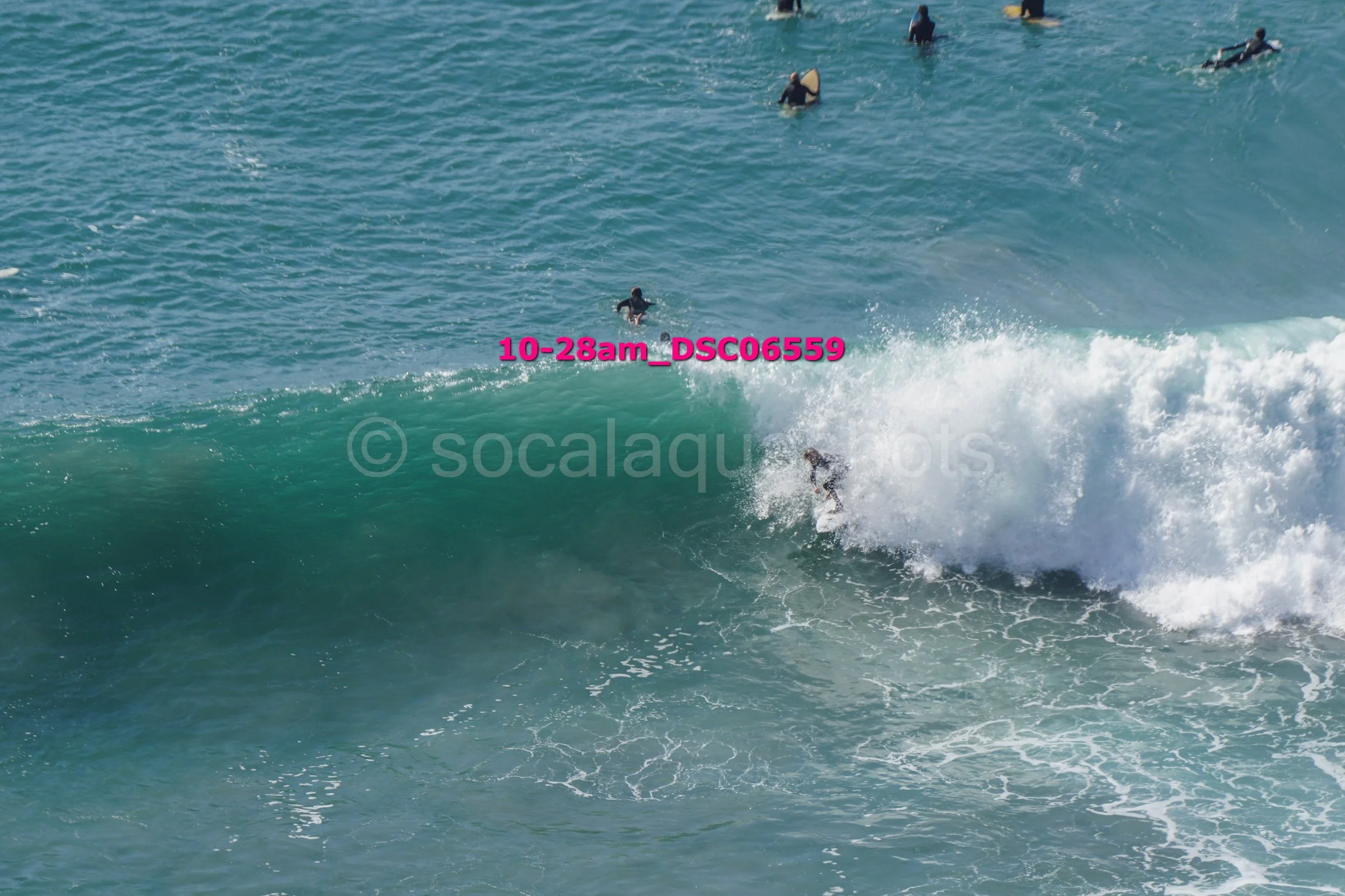 Surfer riding a large wave with several surfers in the water around him
