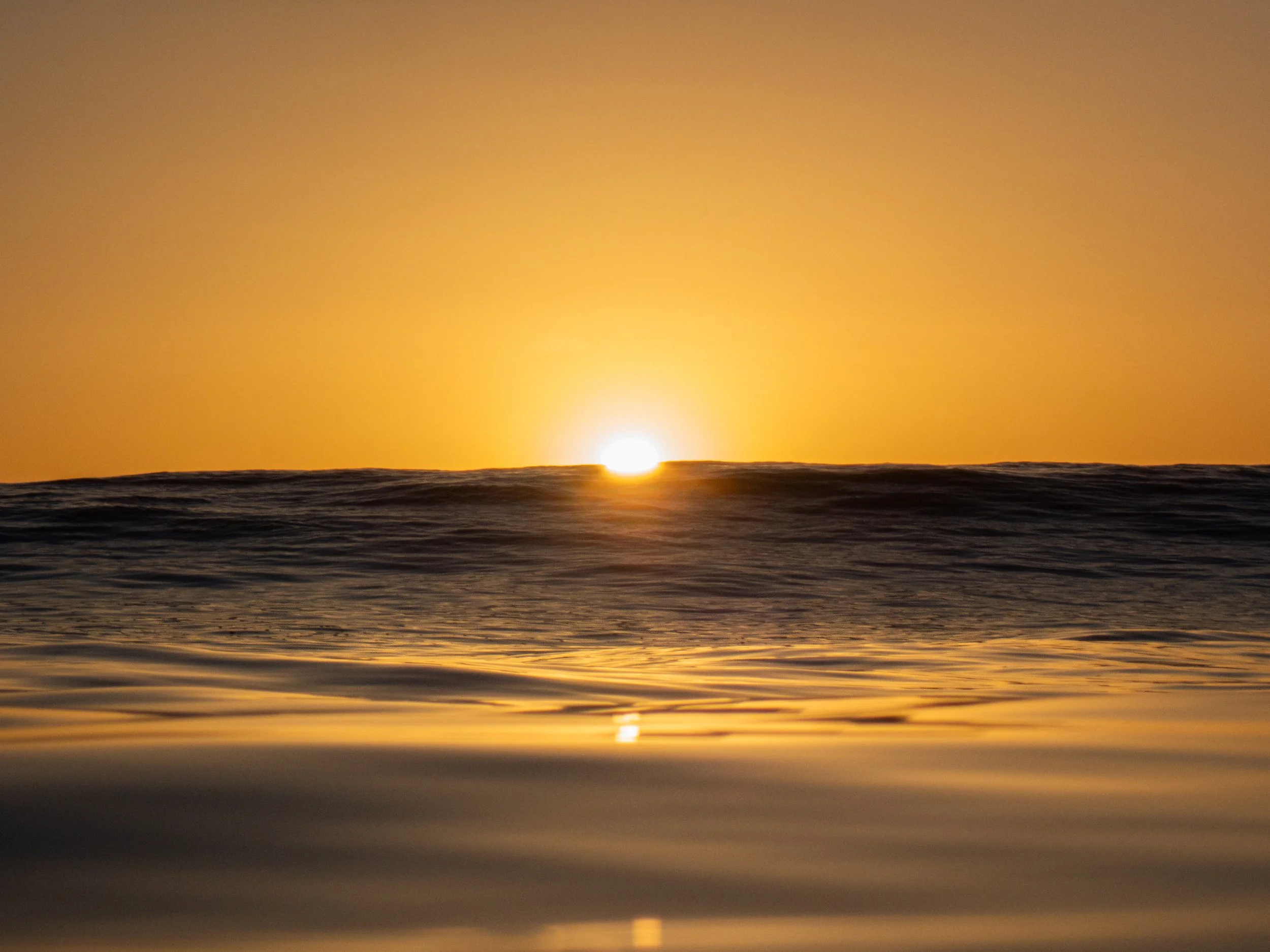 Sunset over the ocean with golden colors reflected on the water.