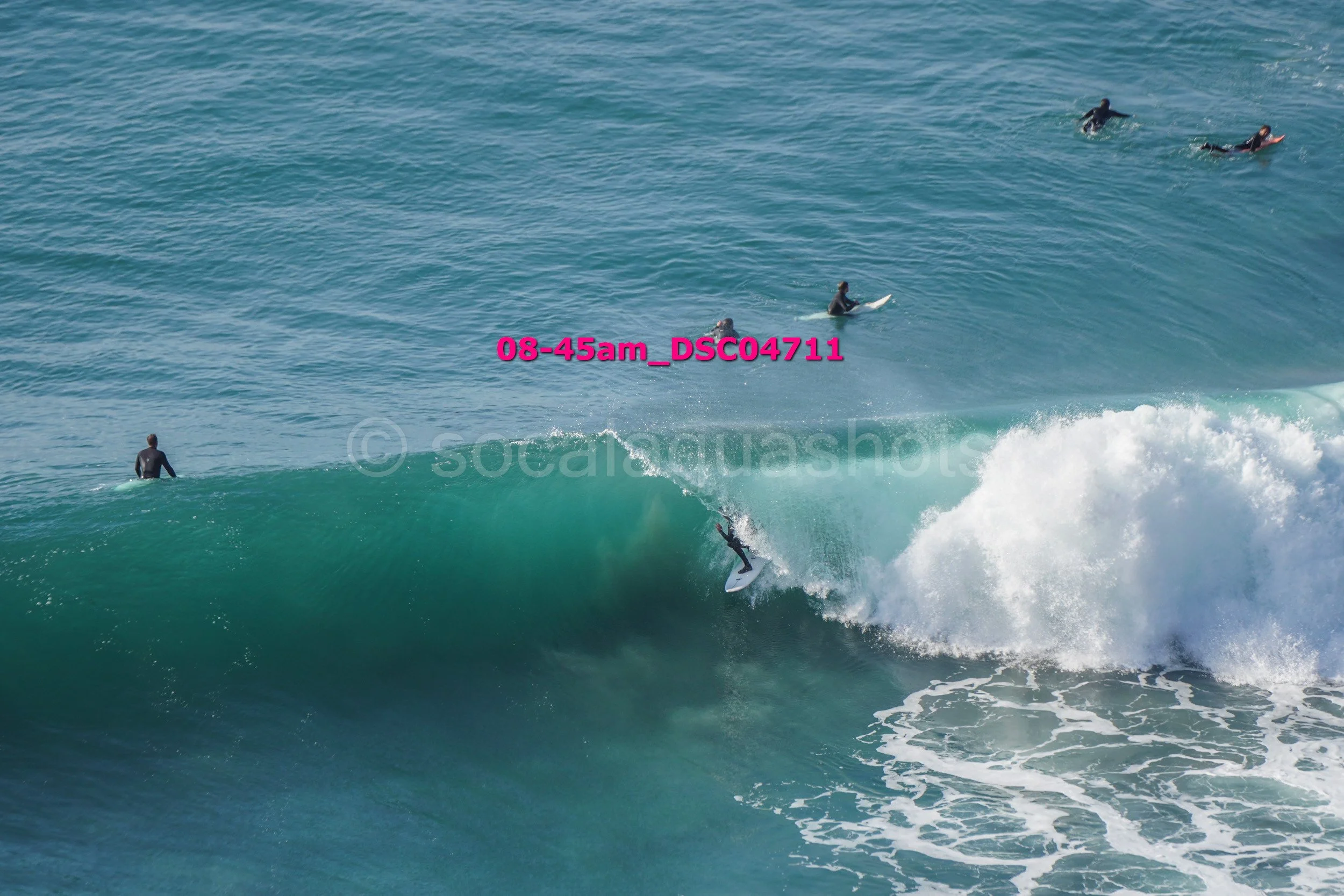 Surfer riding a wave at the beach with other surfers in the water.