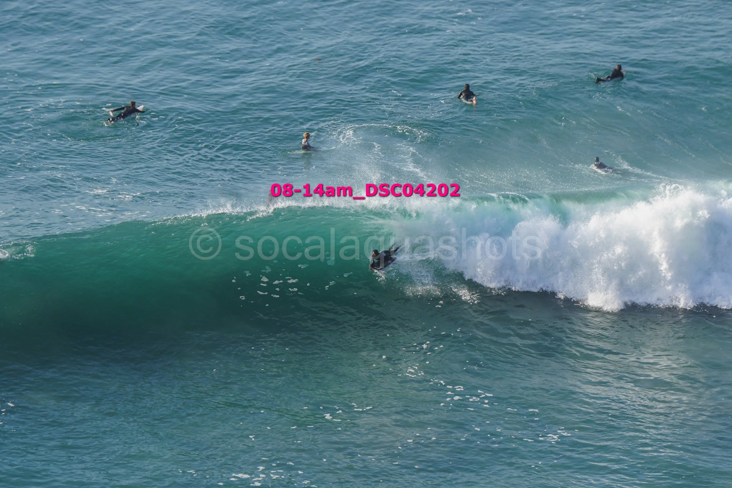 Surfer riding a wave with other surfers in the water nearby.