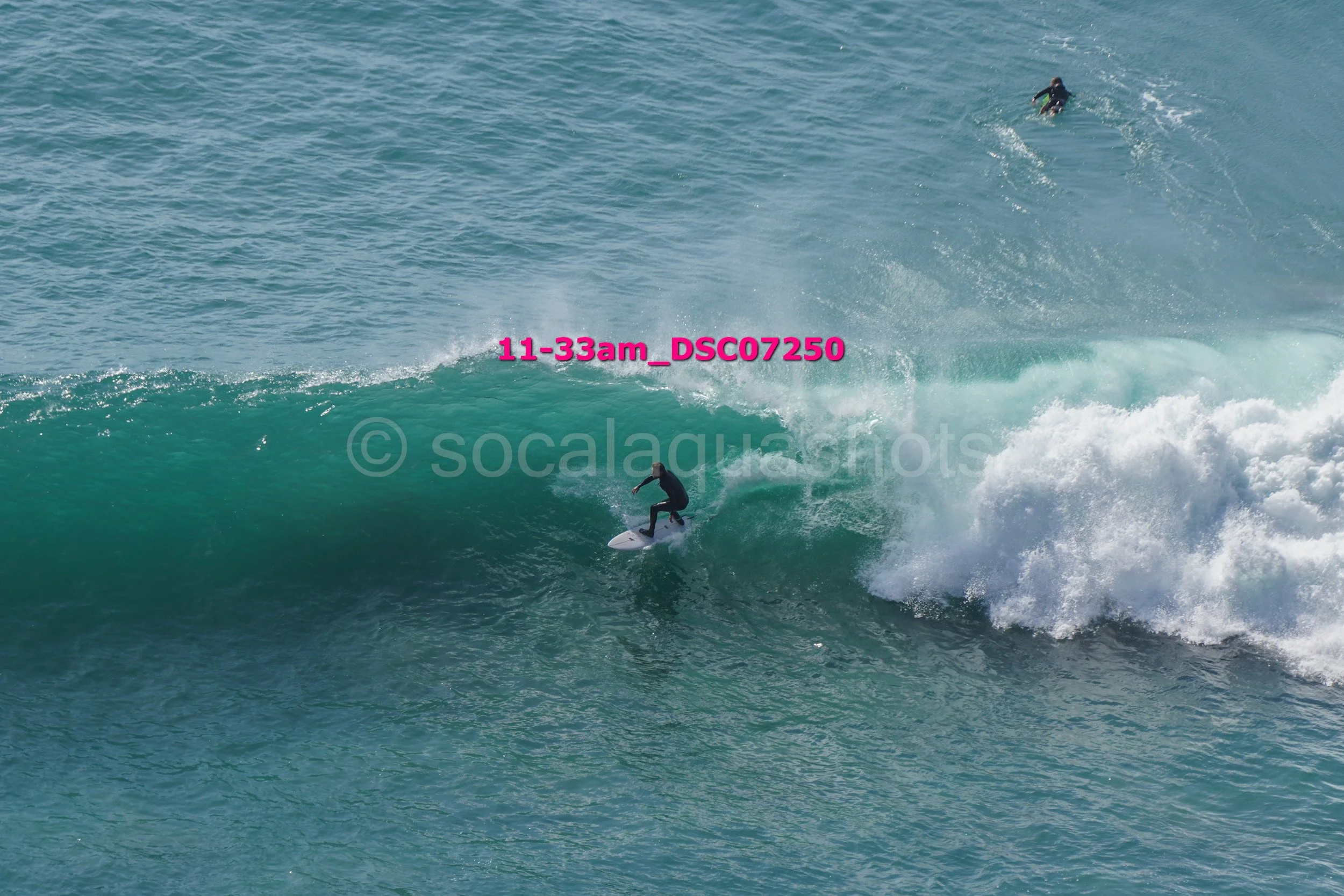 Surfer riding a large wave with another surfer in the distance.