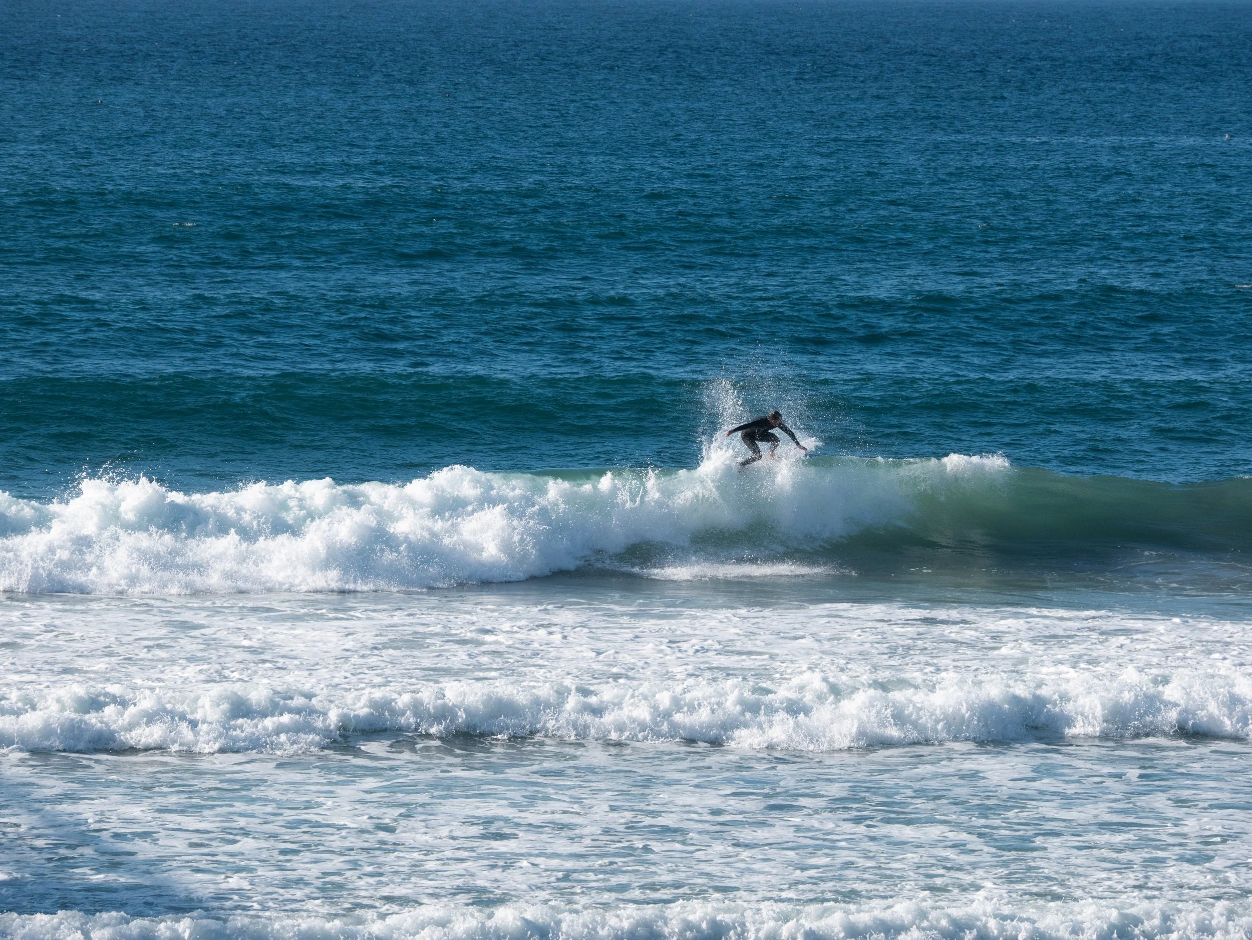Person surfing on a wave in the ocean on a sunny day.