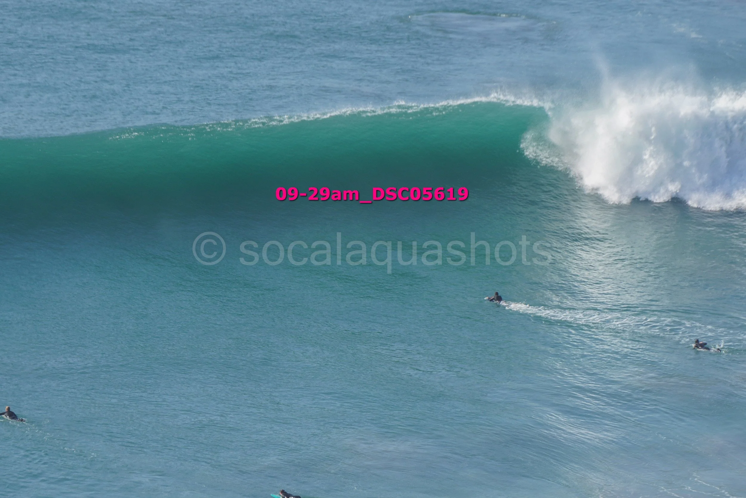 Large ocean wave with surfers in the water.
