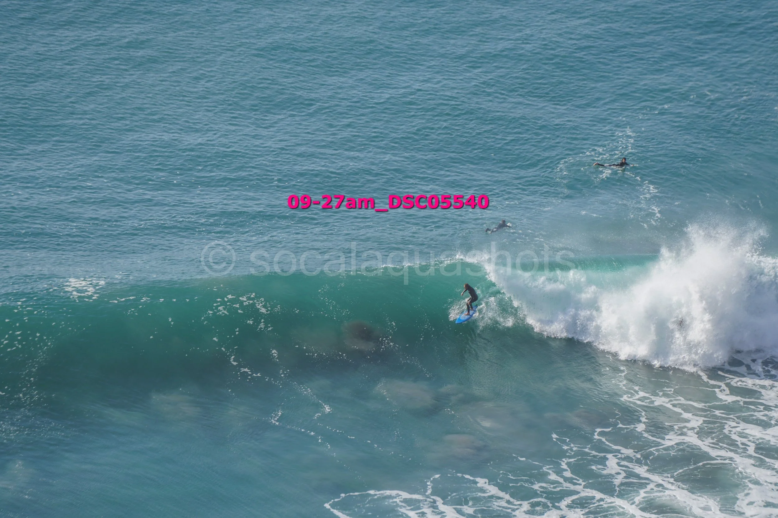 Surfer riding a wave with three other surfers in the water nearby
