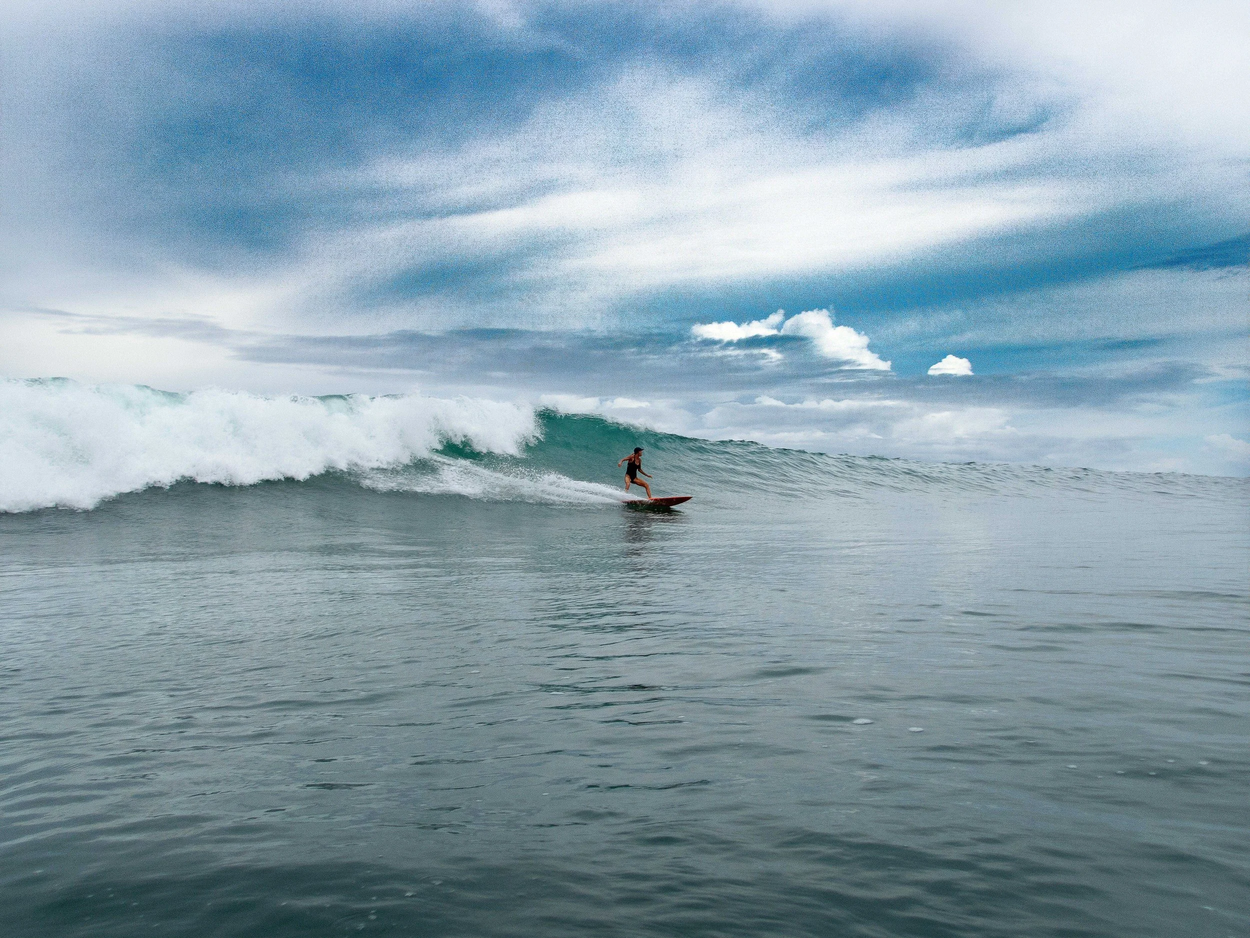 Surfer riding a wave under a cloudy sky