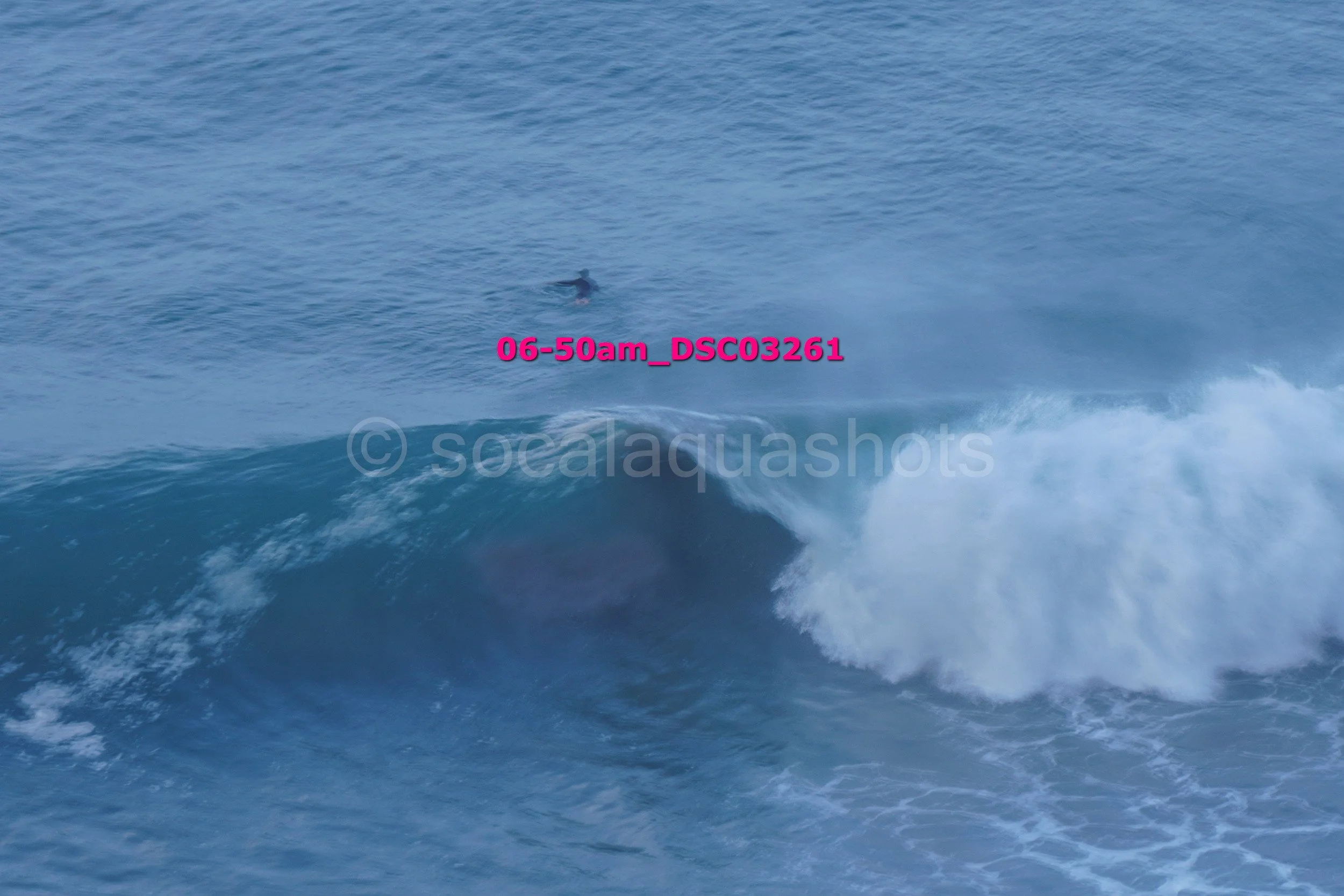 A surfer riding a wave in the ocean, viewed from above.