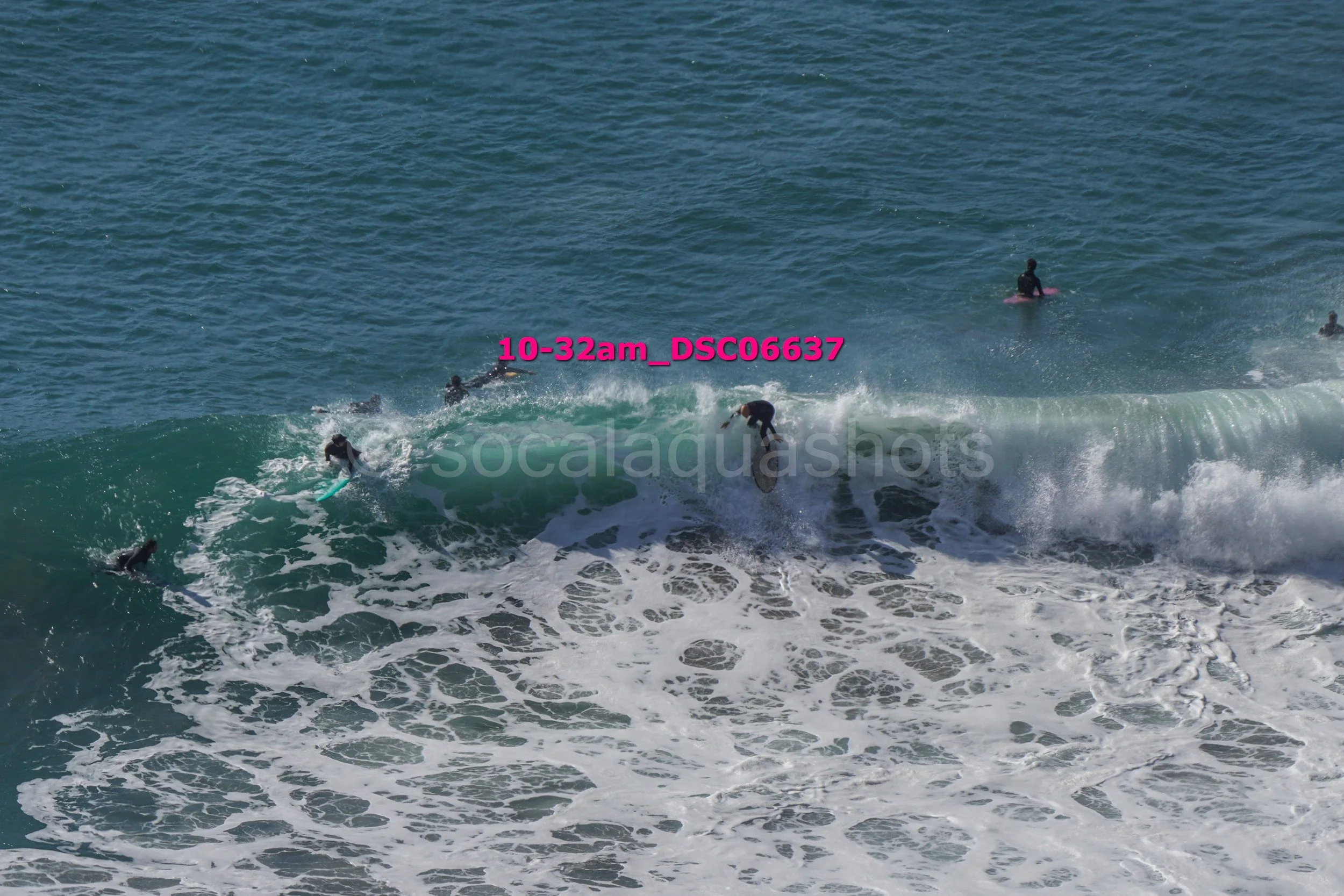 A group of surfers riding a large wave in the ocean during daytime.