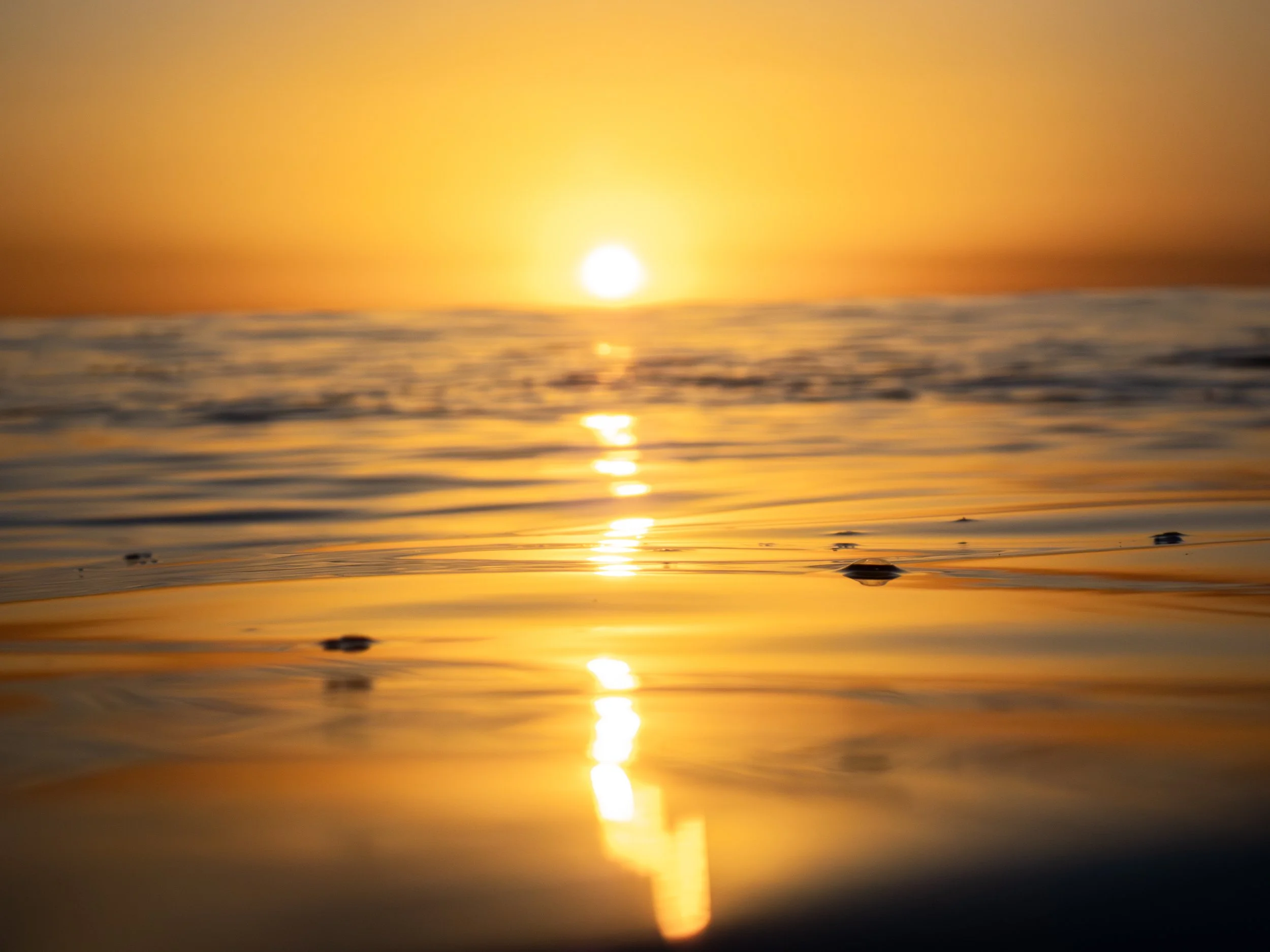 Sunset over the ocean with reflections on the water.