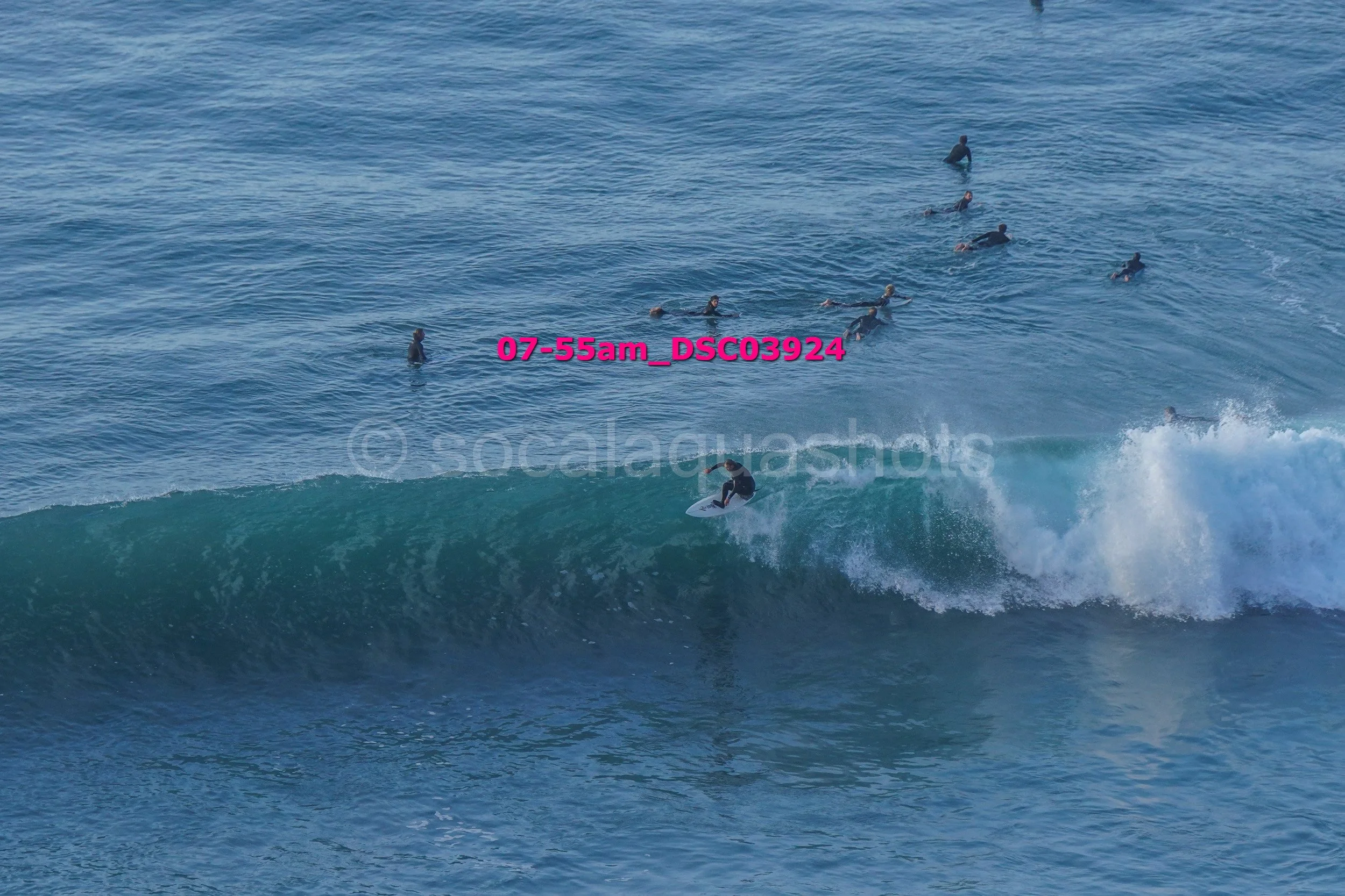 Surfer riding a wave with multiple surfers in the background in the ocean.