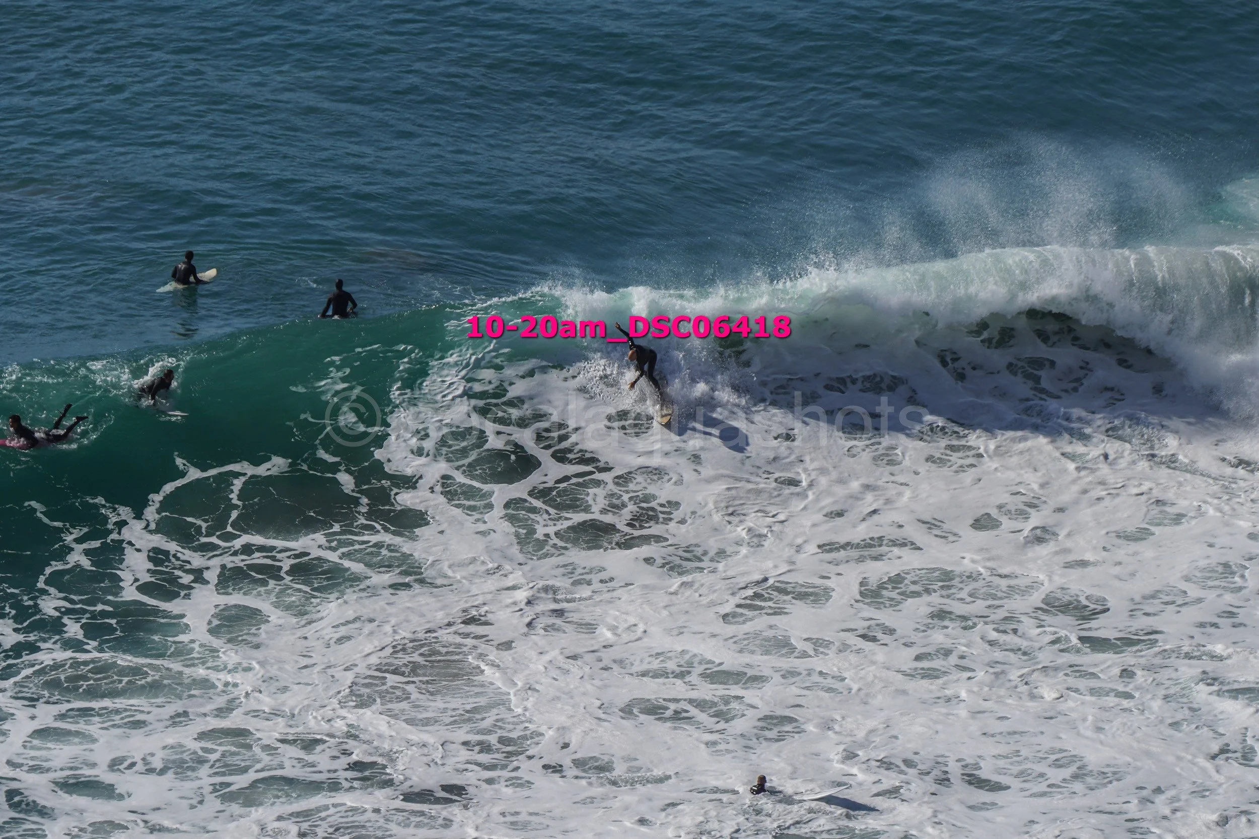 Surfer riding a wave with other surfers in the ocean, with the text '10-20am_DSC06418' overlaid in pink.