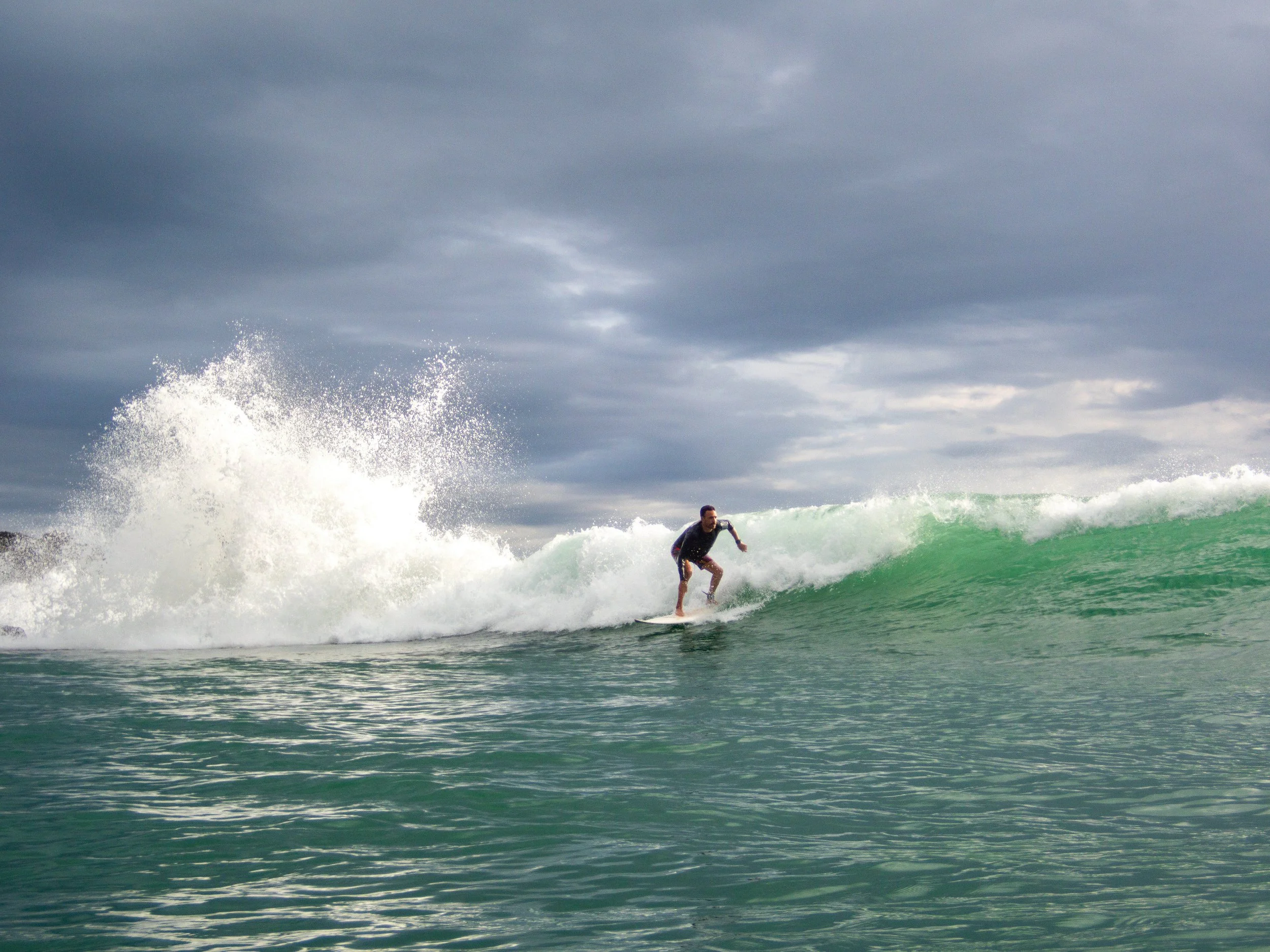 Surfer riding a wave on a cloudy day