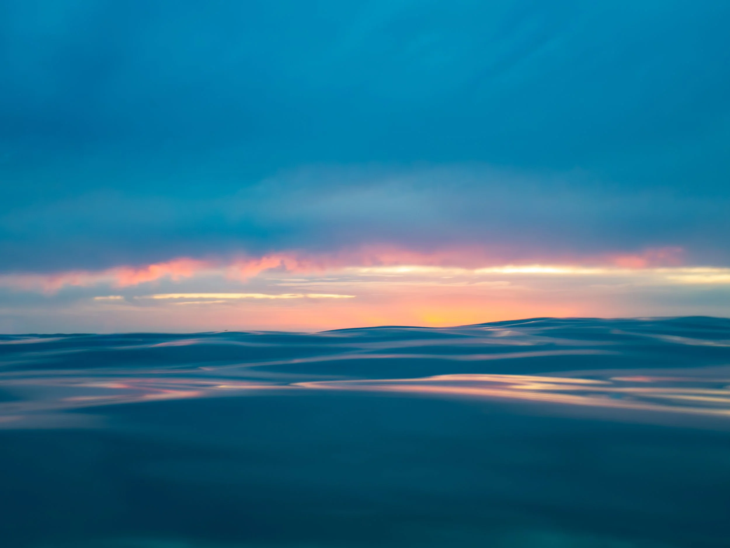 Ocean waves at sunset with a cloudy sky