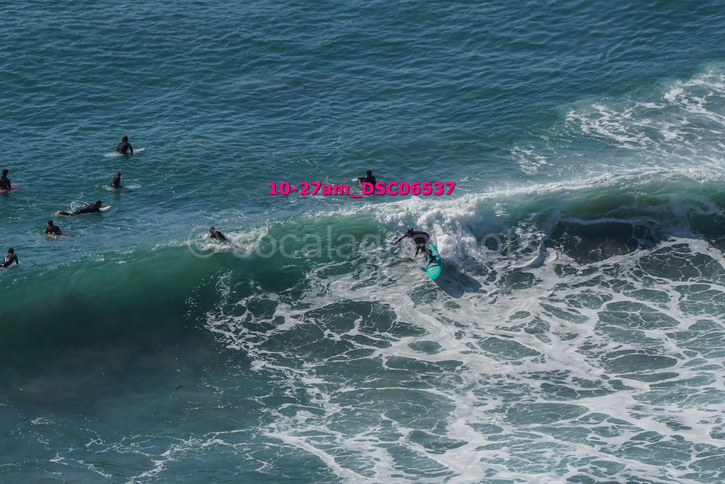 Surfer riding a wave with several people in the water watching in the background.