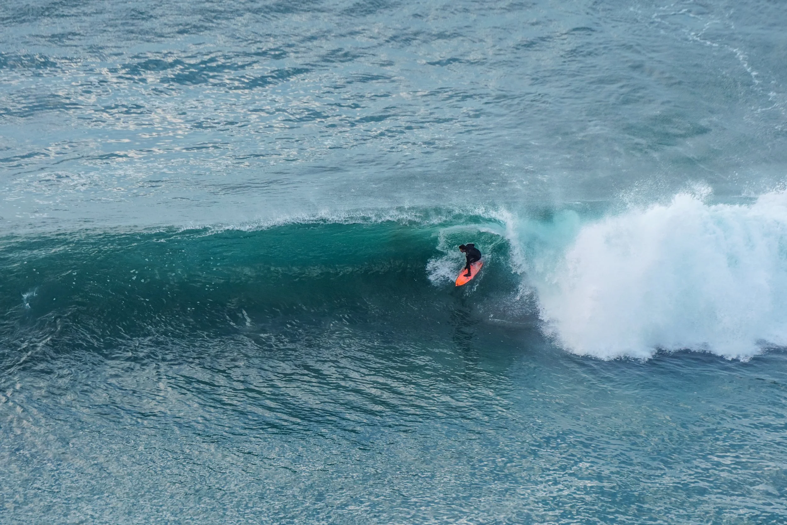 Surfer riding inside the barrel of a large wave in the ocean.