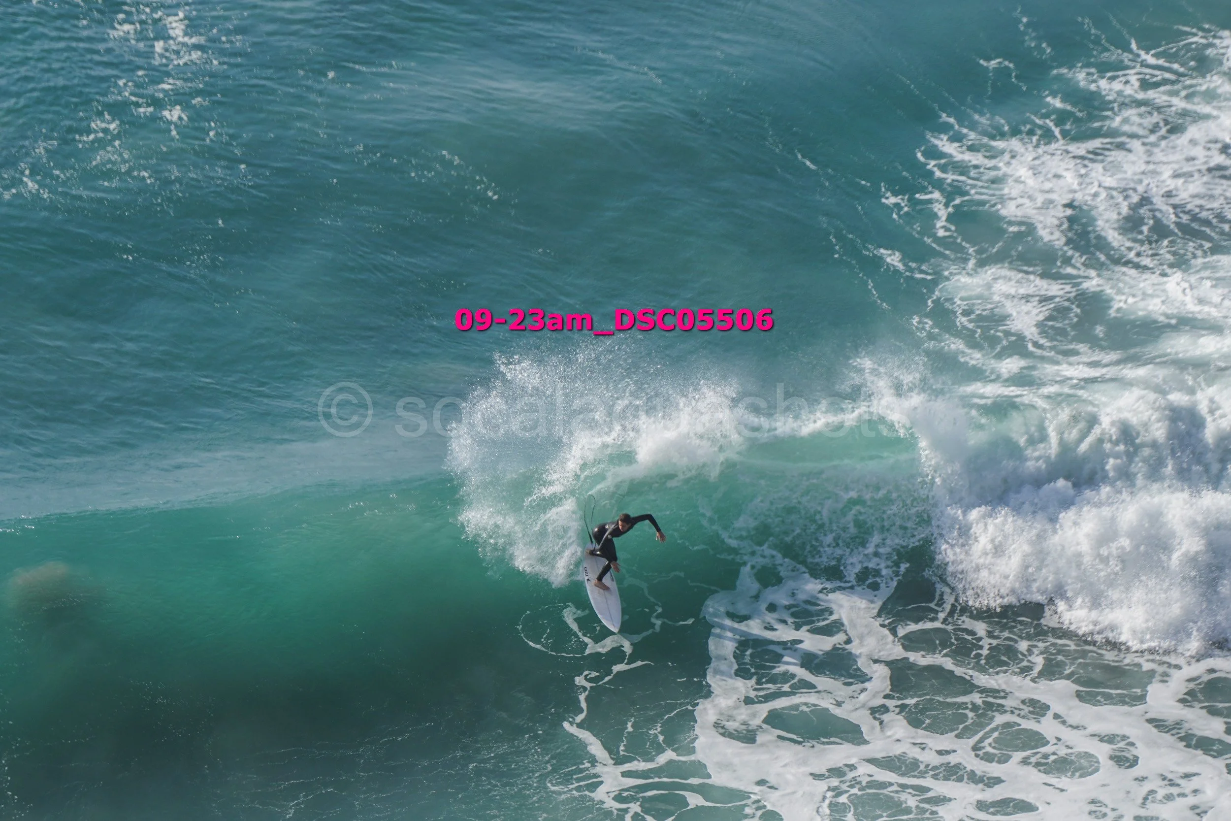 A person surfing on a large ocean wave with white foam.
