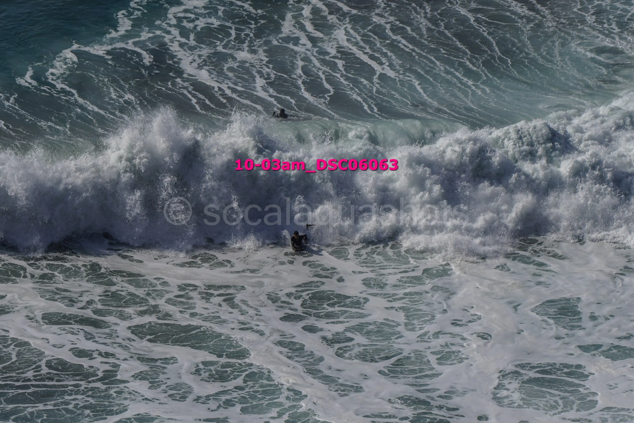 Surfers riding and struggling against large ocean waves.