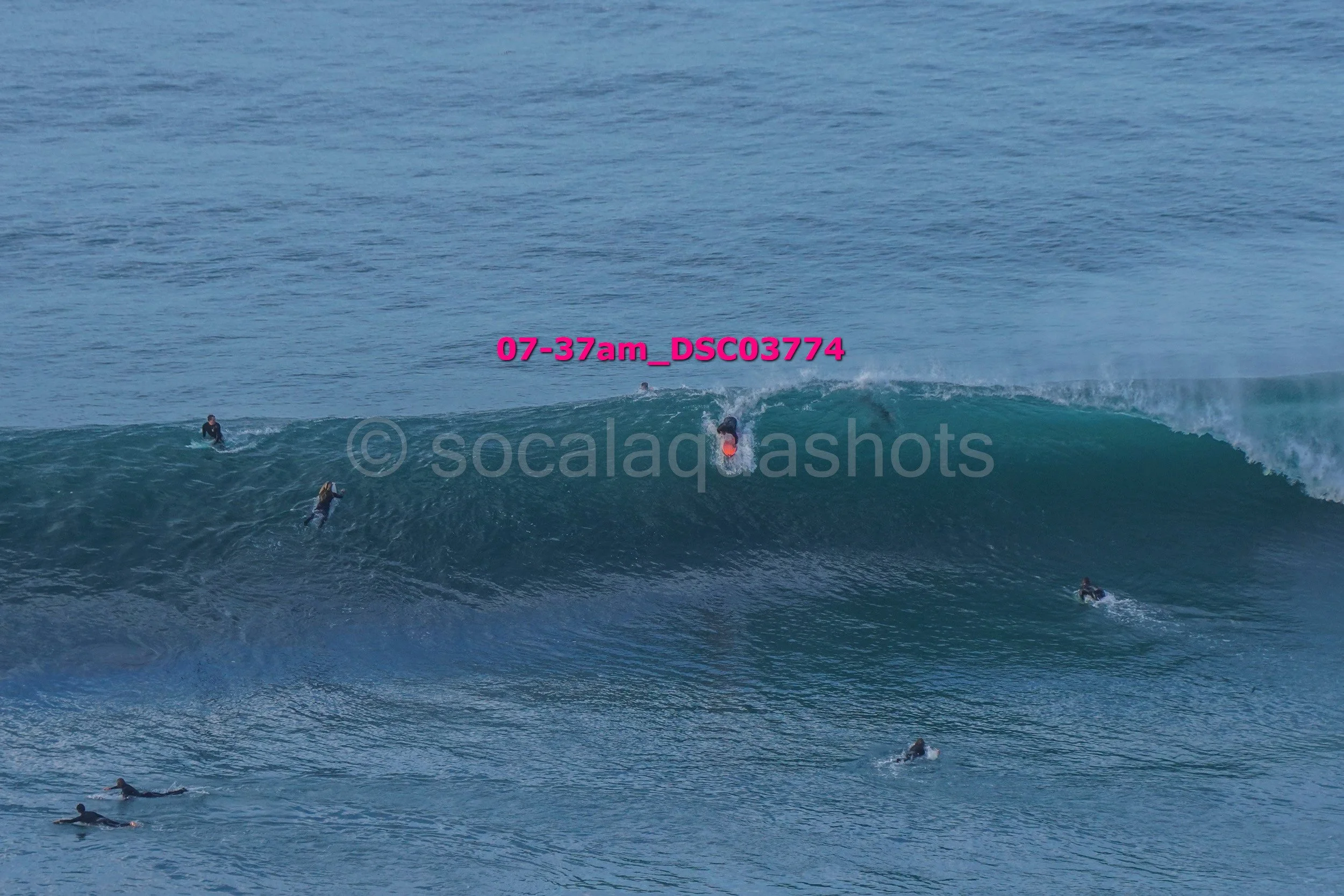 Surfers riding and paddling on ocean waves.