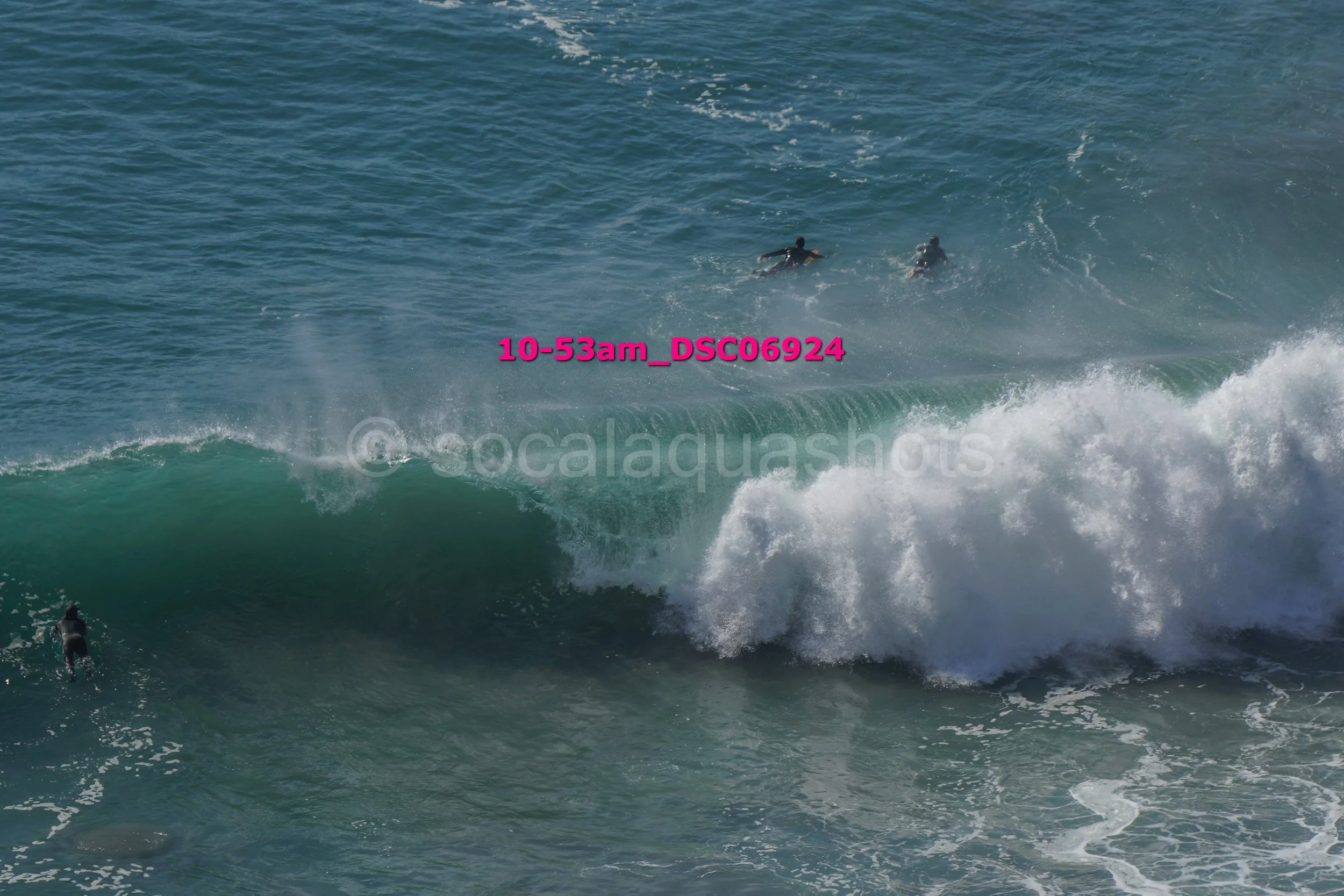 People surfing large waves in the ocean, some are riding the waves while others are paddling.