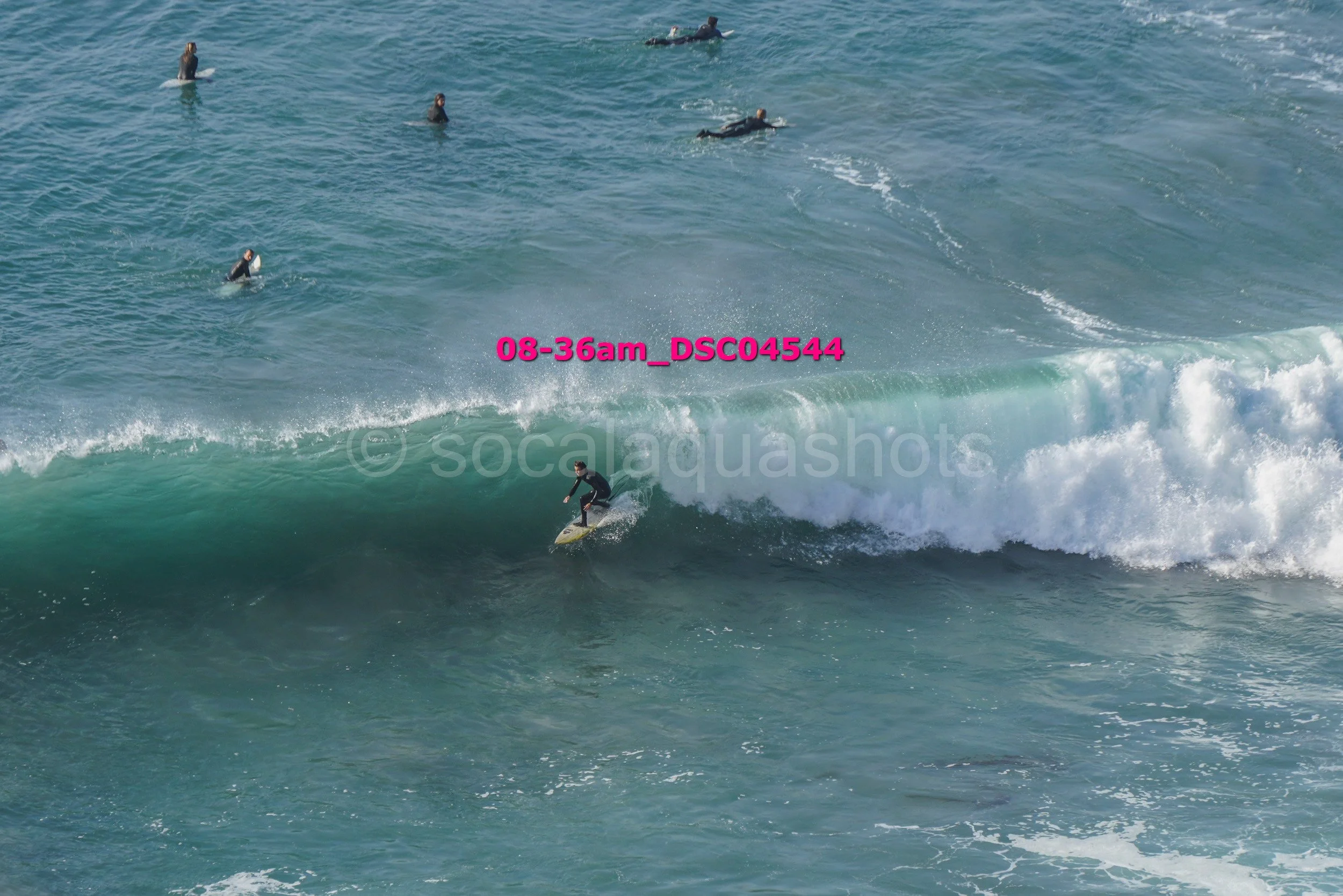 Surfer riding a wave while several surfers wait in the water