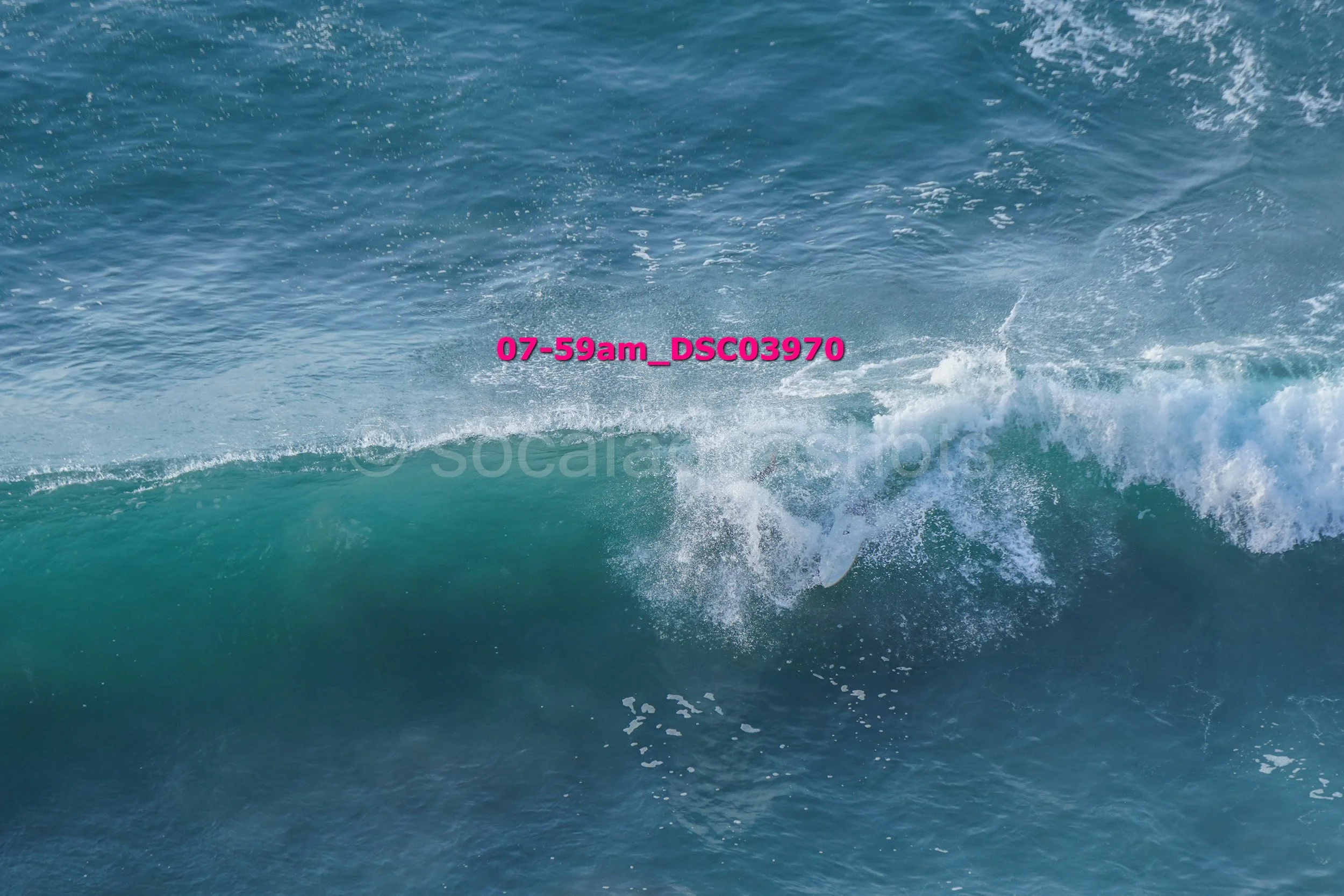 A surfer riding a wave in the ocean with white foam spray.