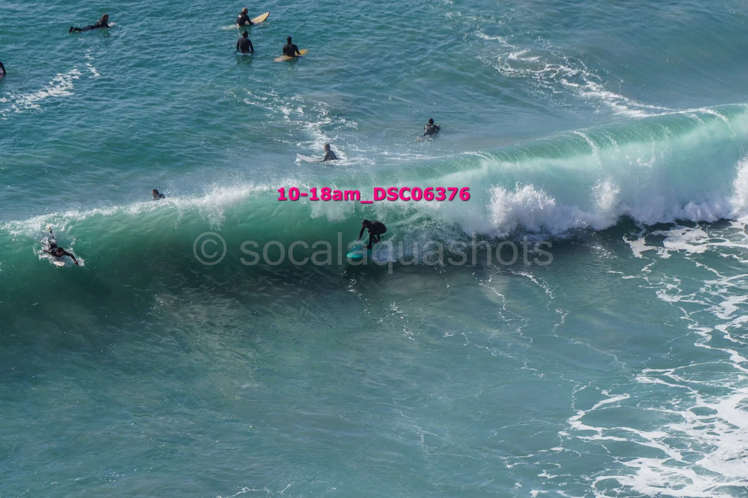 Multiple surfers riding and waiting for waves in the ocean during daytime.