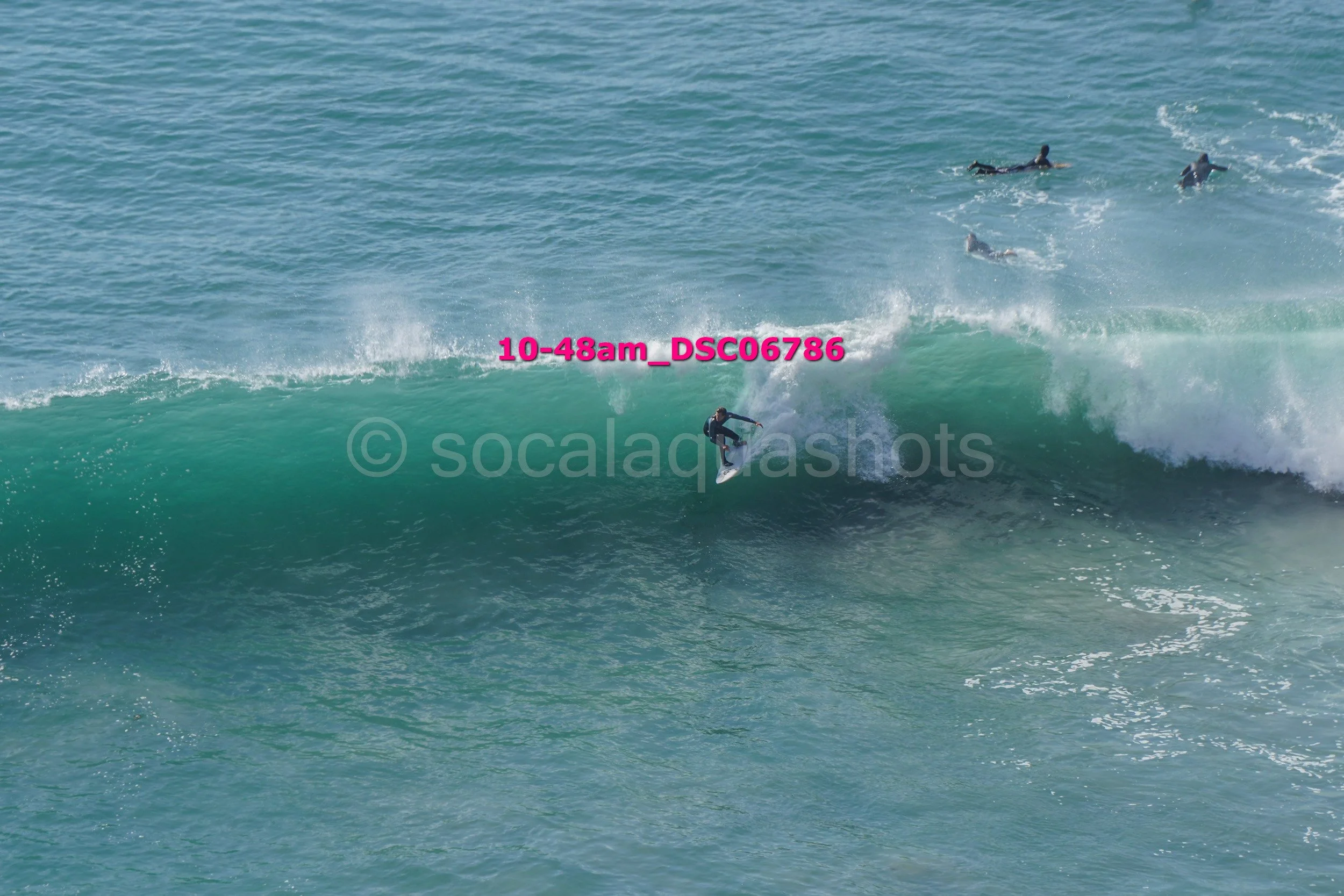 Surfer riding a wave with several surfers in the water in the background