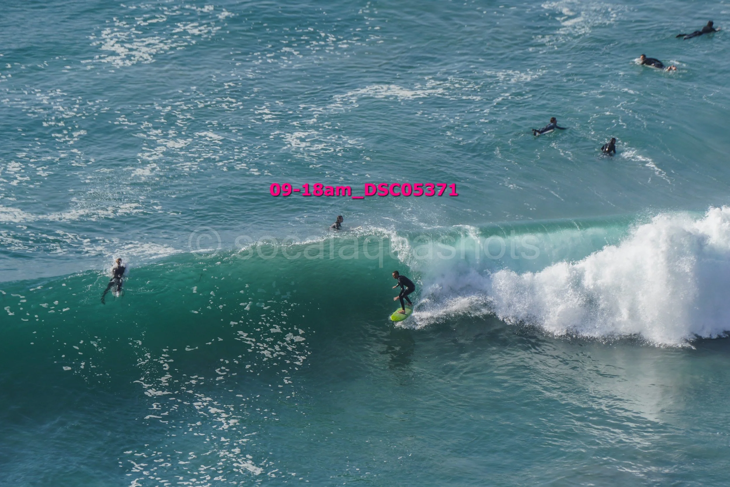 A person surfing on a wave in the ocean with several other surfers in the background.