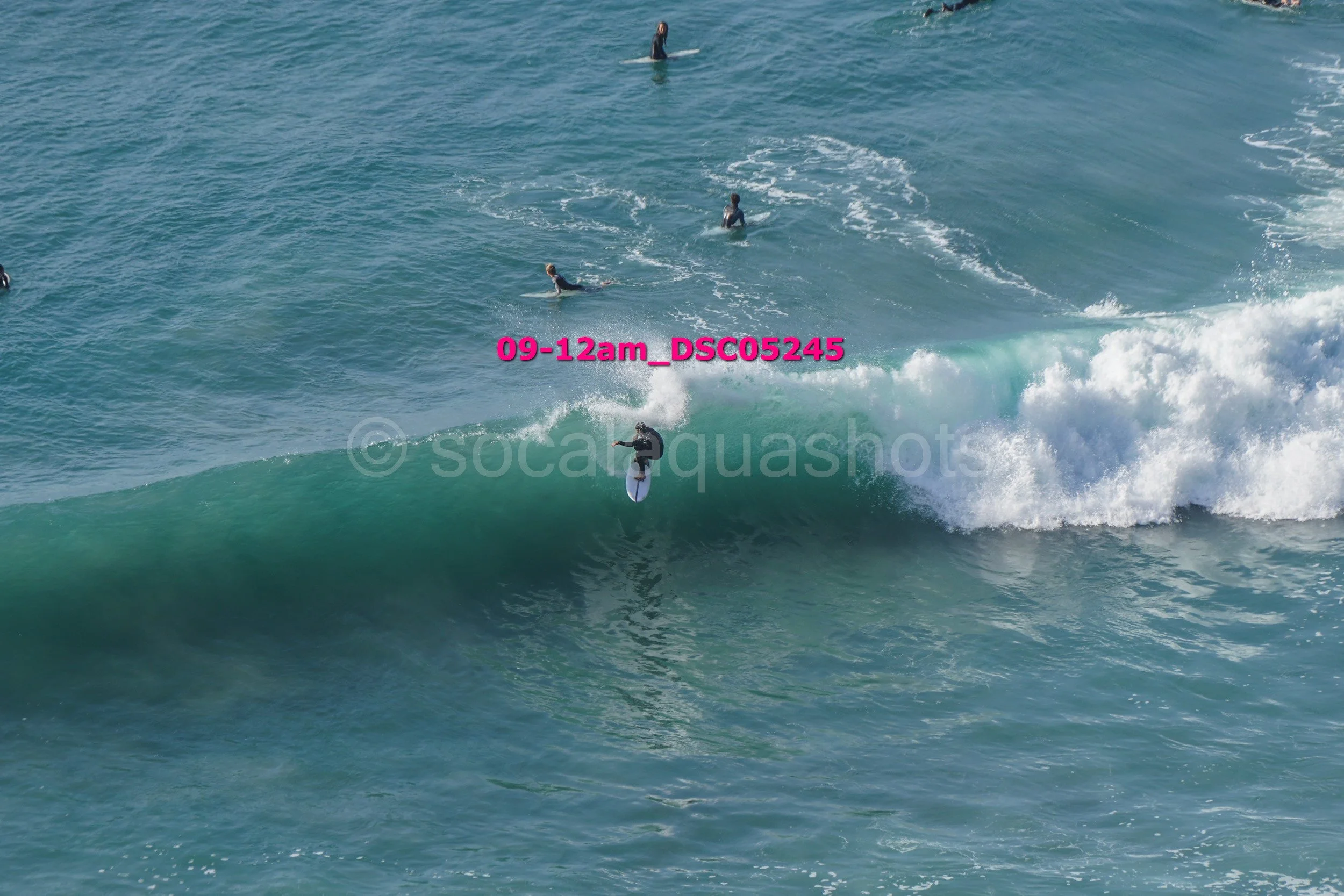 A person surfing on a wave with others in the water nearby.