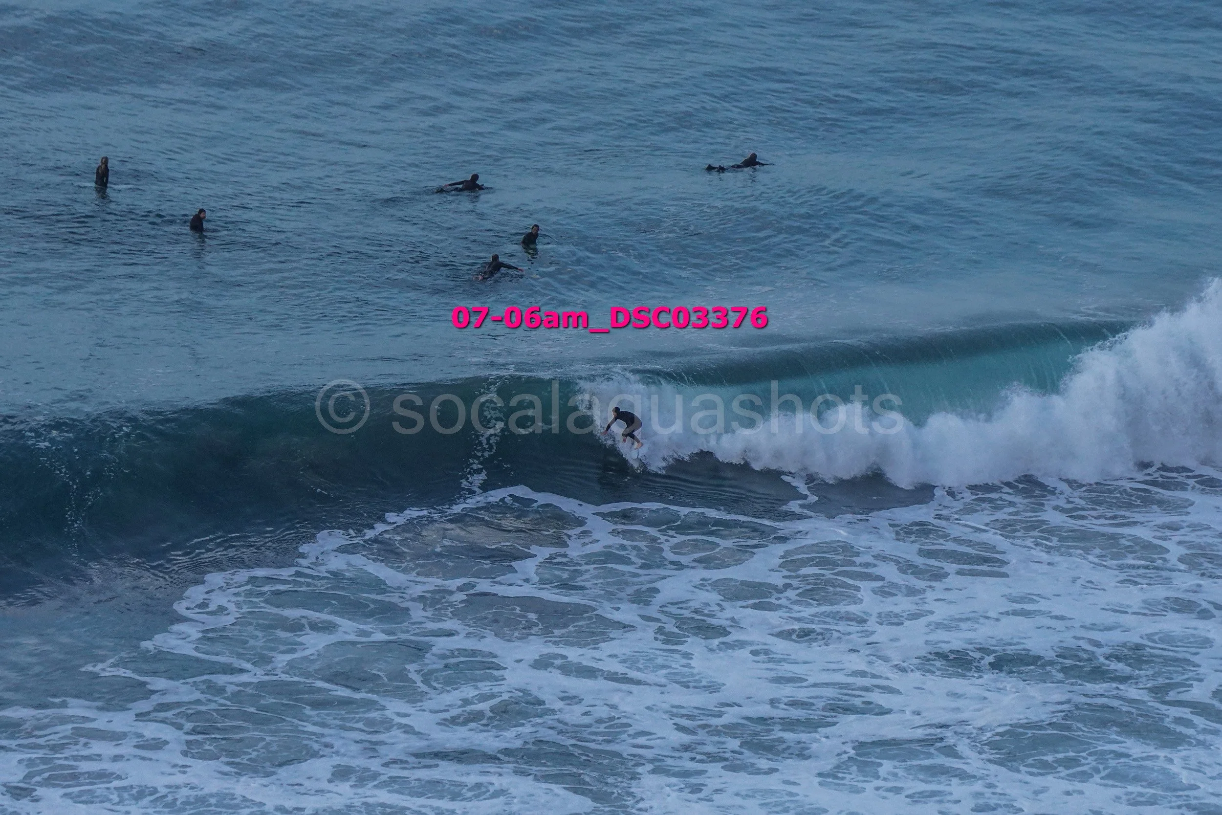 Surfer riding a wave with several surfers in the water in the background.