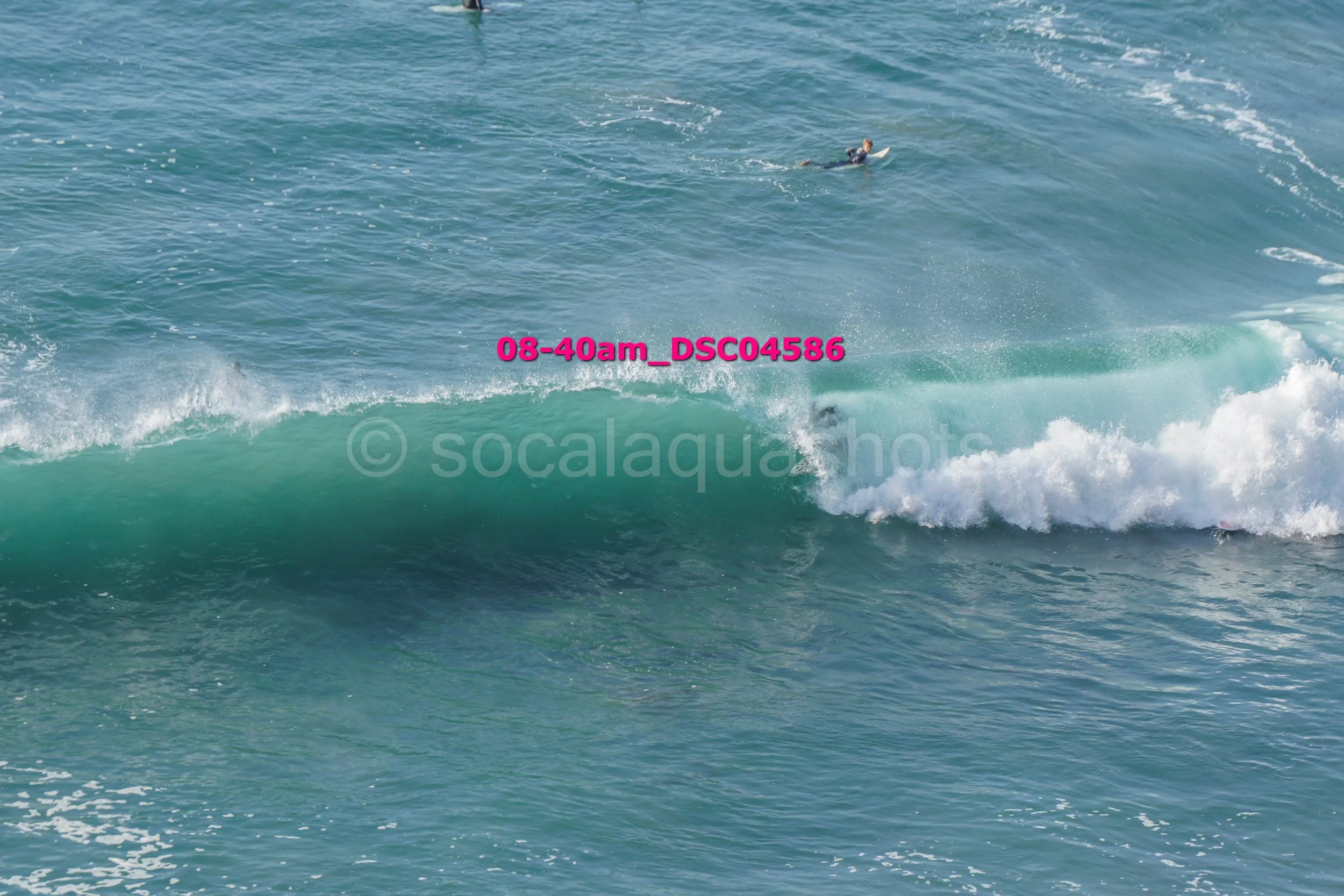 A person is surfing on a wave in the ocean, seen from a distance.