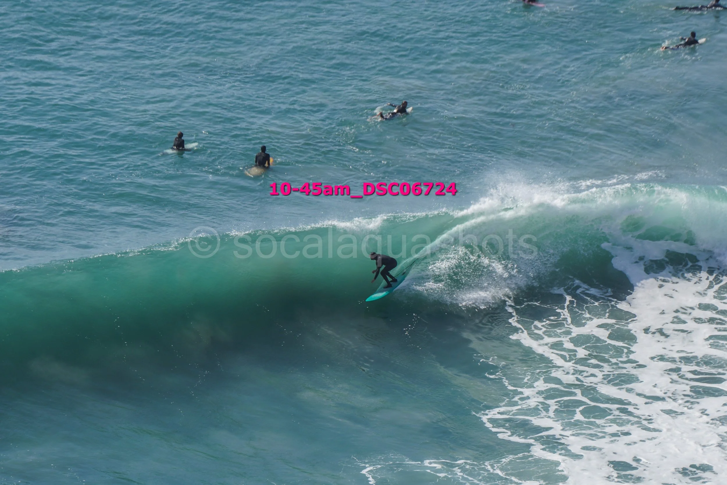 A person surfing on a wave with several other surfers in the water in the background.