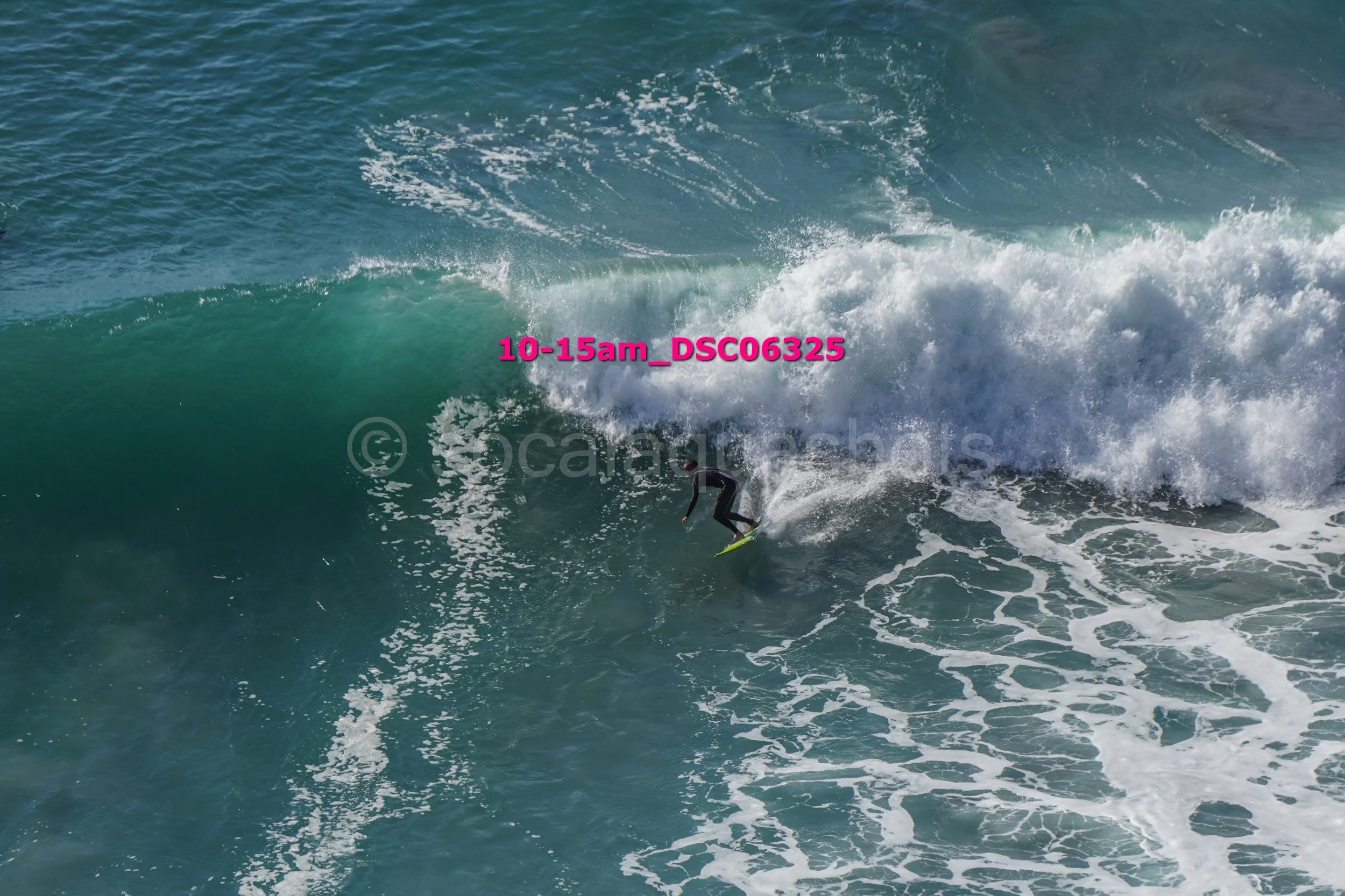 Surfer in a wetsuit riding a large wave in the ocean, with white foam and spray.