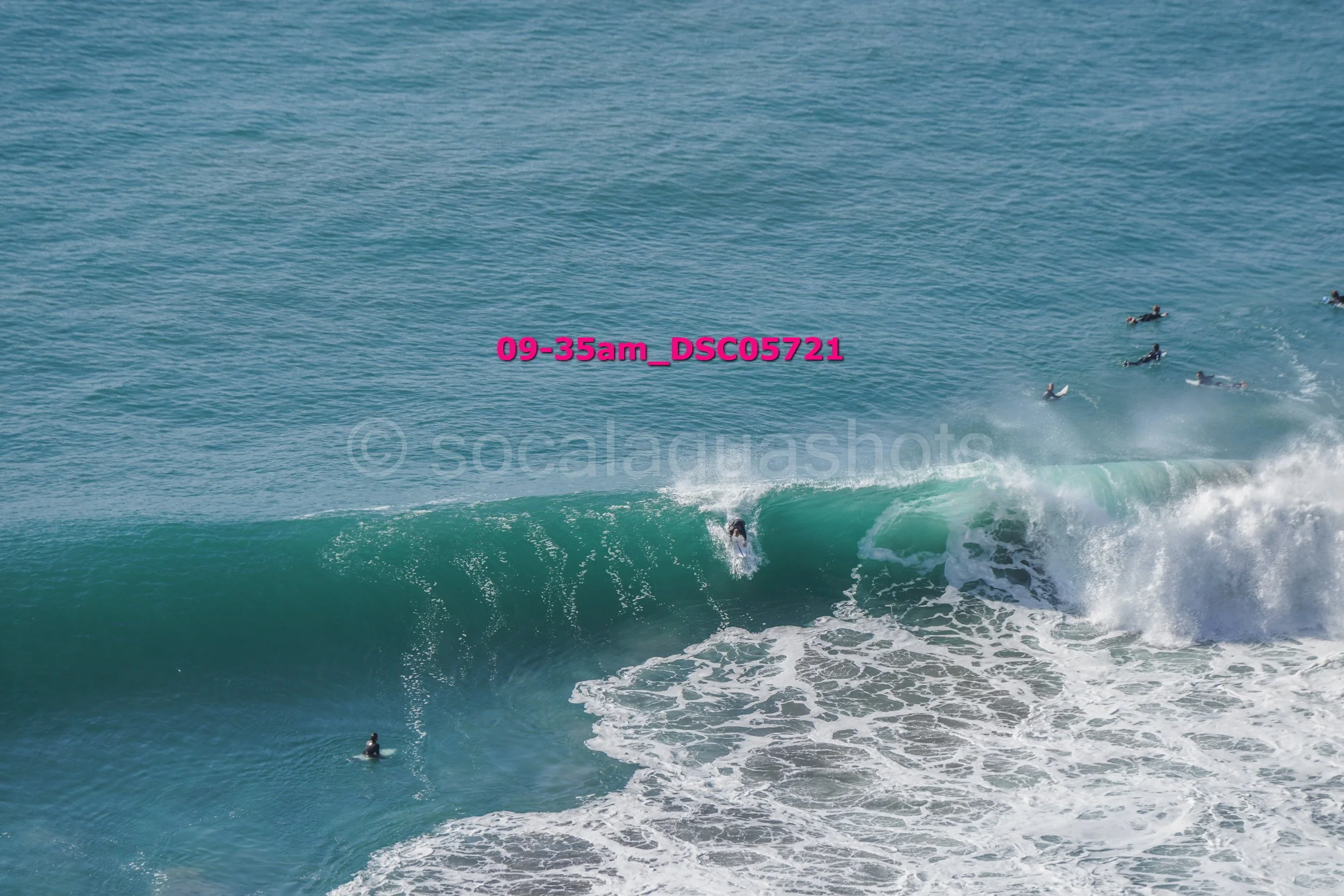 A group of surfers in the ocean. One surfer riding a wave, others in the water, some holding surfboards.