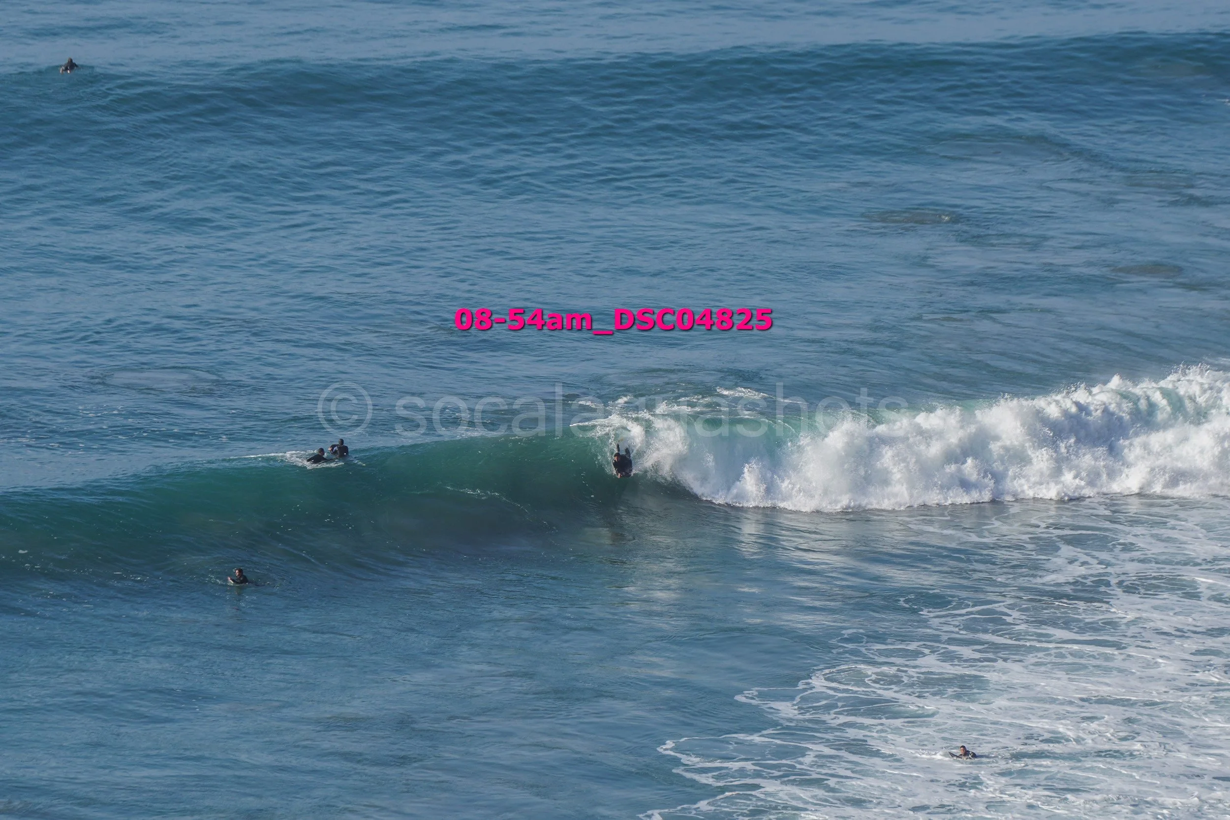Surfers riding ocean waves off a beach in the early morning.