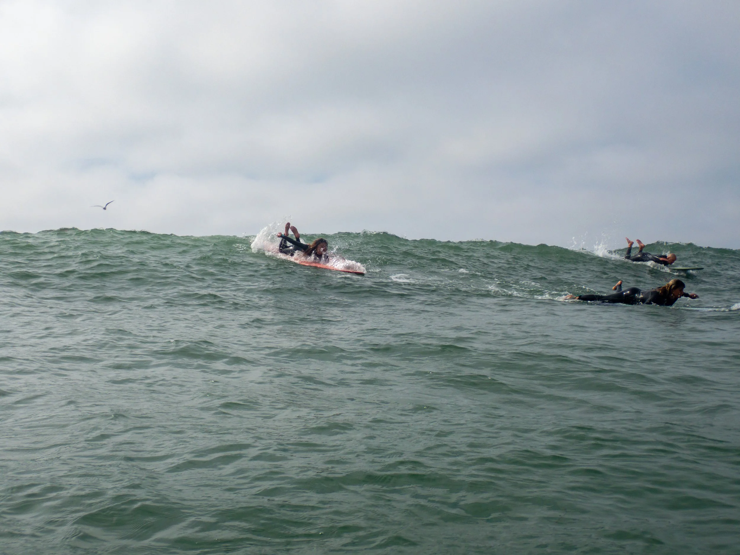 People surfing on the ocean waves under cloudy sky.