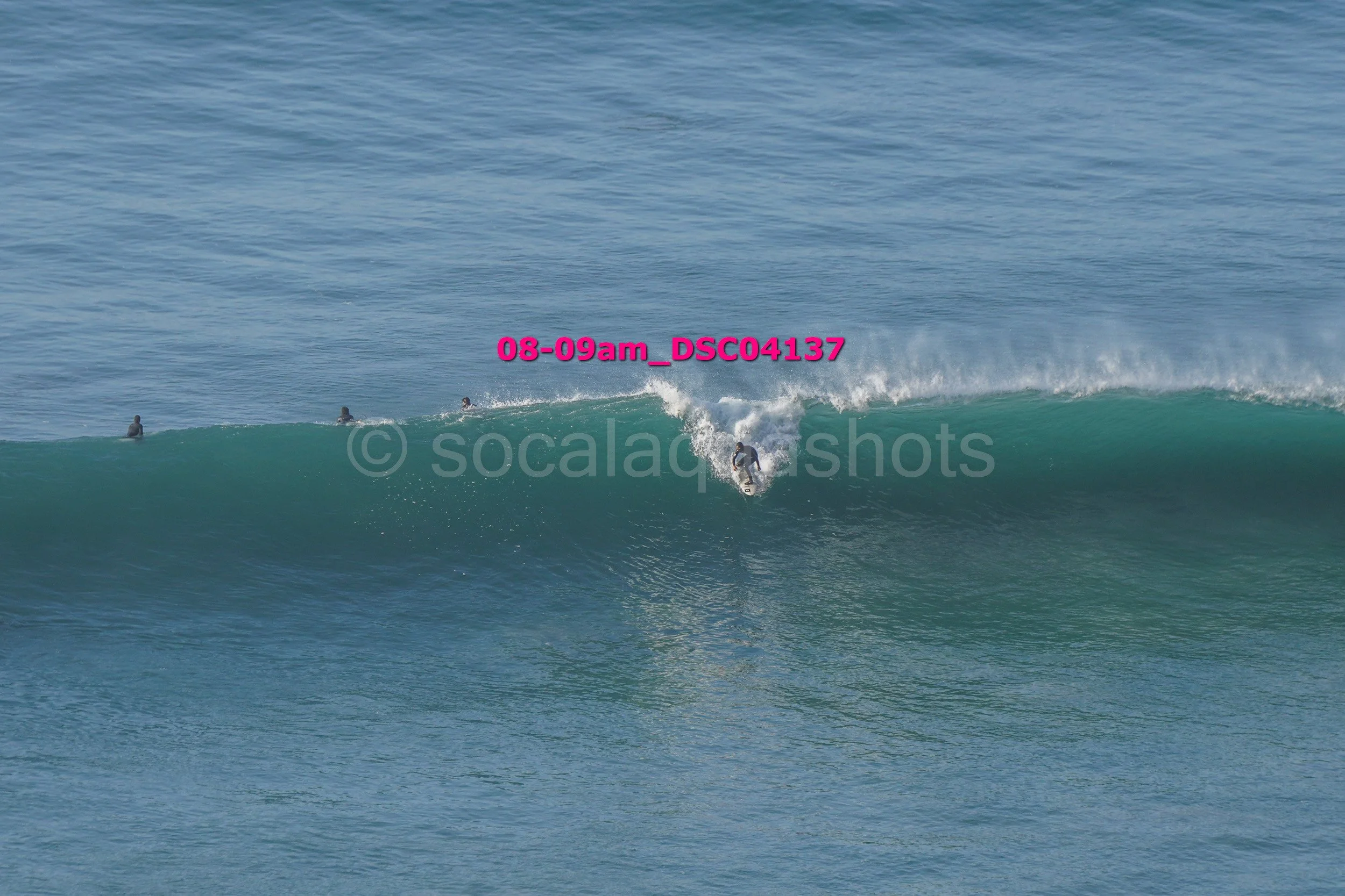 Surfer riding a wave with onlookers in the water