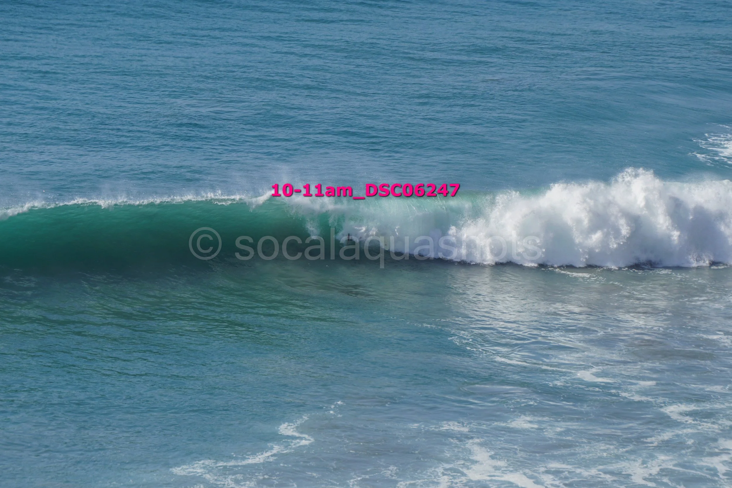 Waves crashing in the ocean with a part of a surfboard visible behind the waves.
