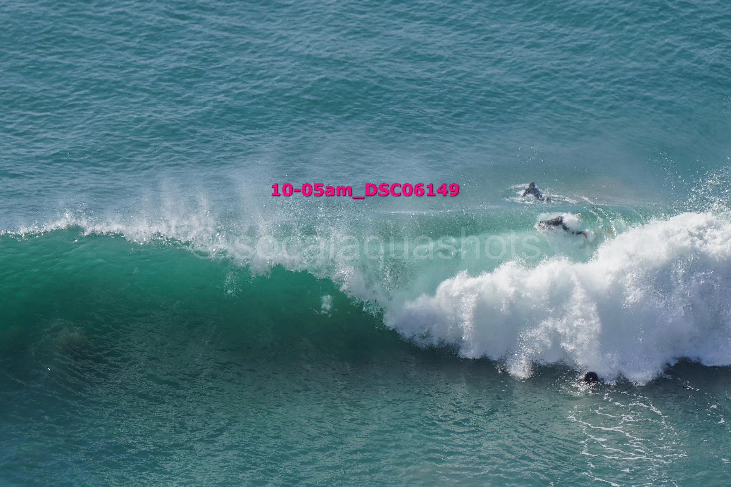 Three surfers riding a large wave in the ocean.