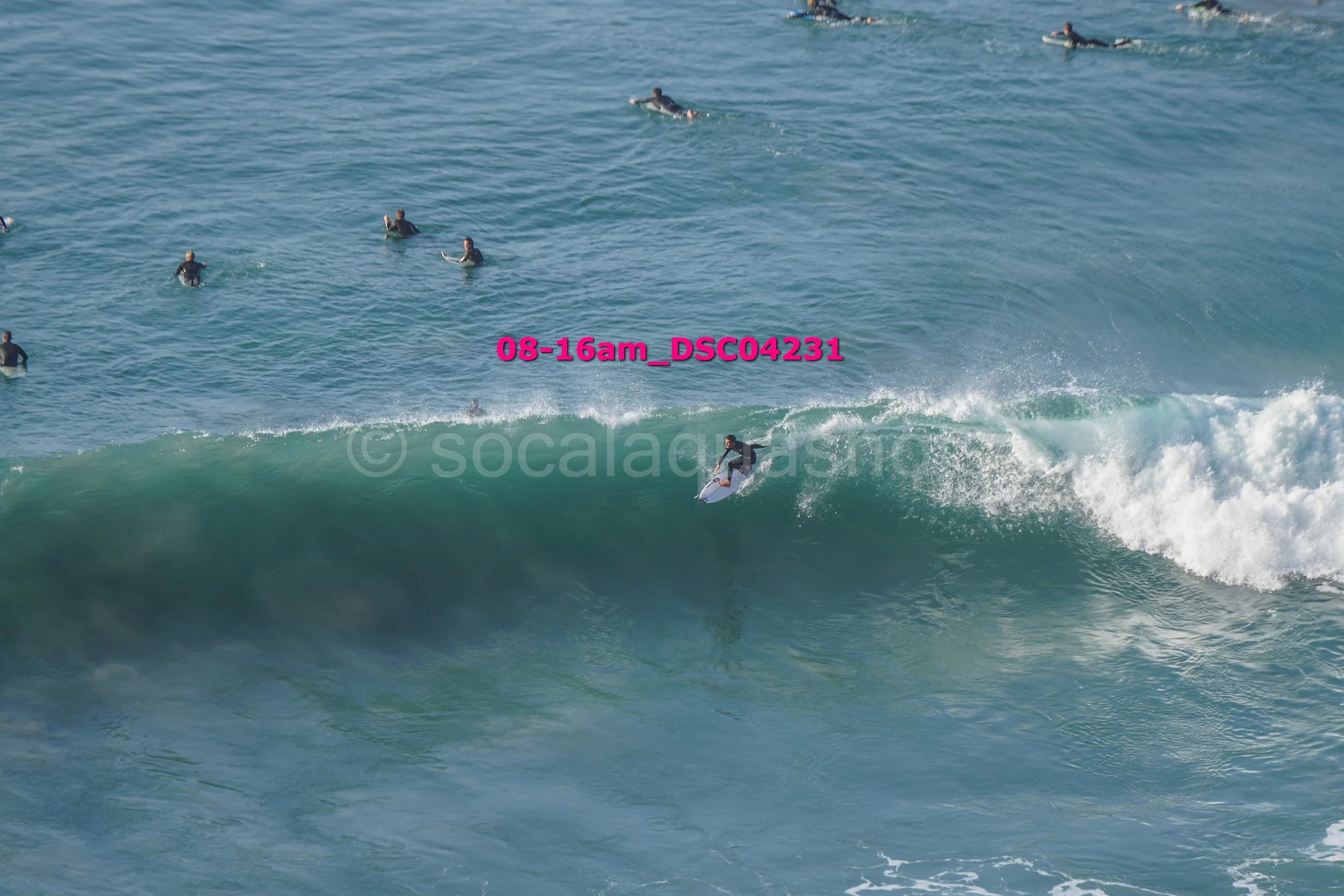 A person surfing on a large wave in the ocean with several other surfers in the background.