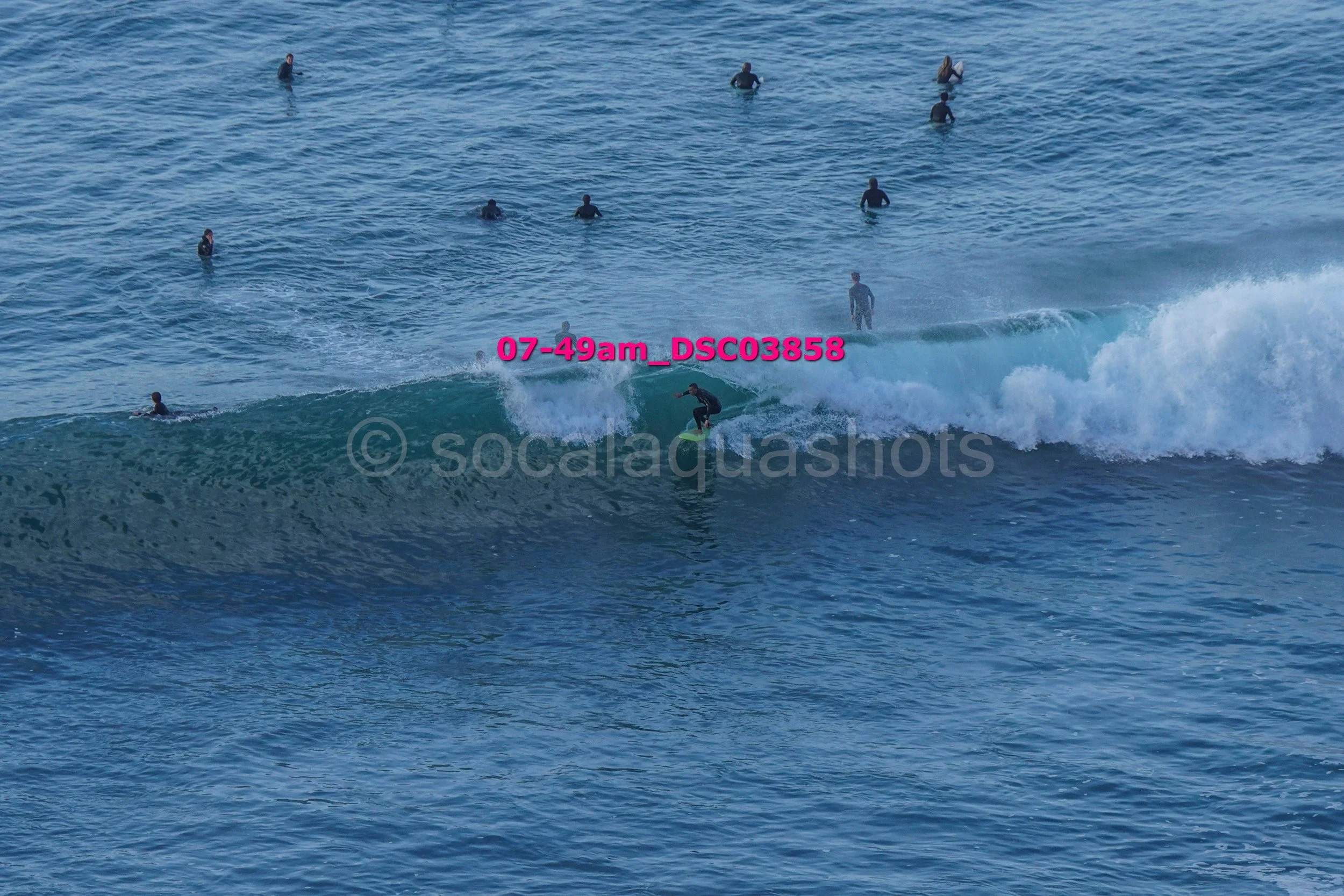 A person surfing a wave while multiple other surfers are in the water in the background.