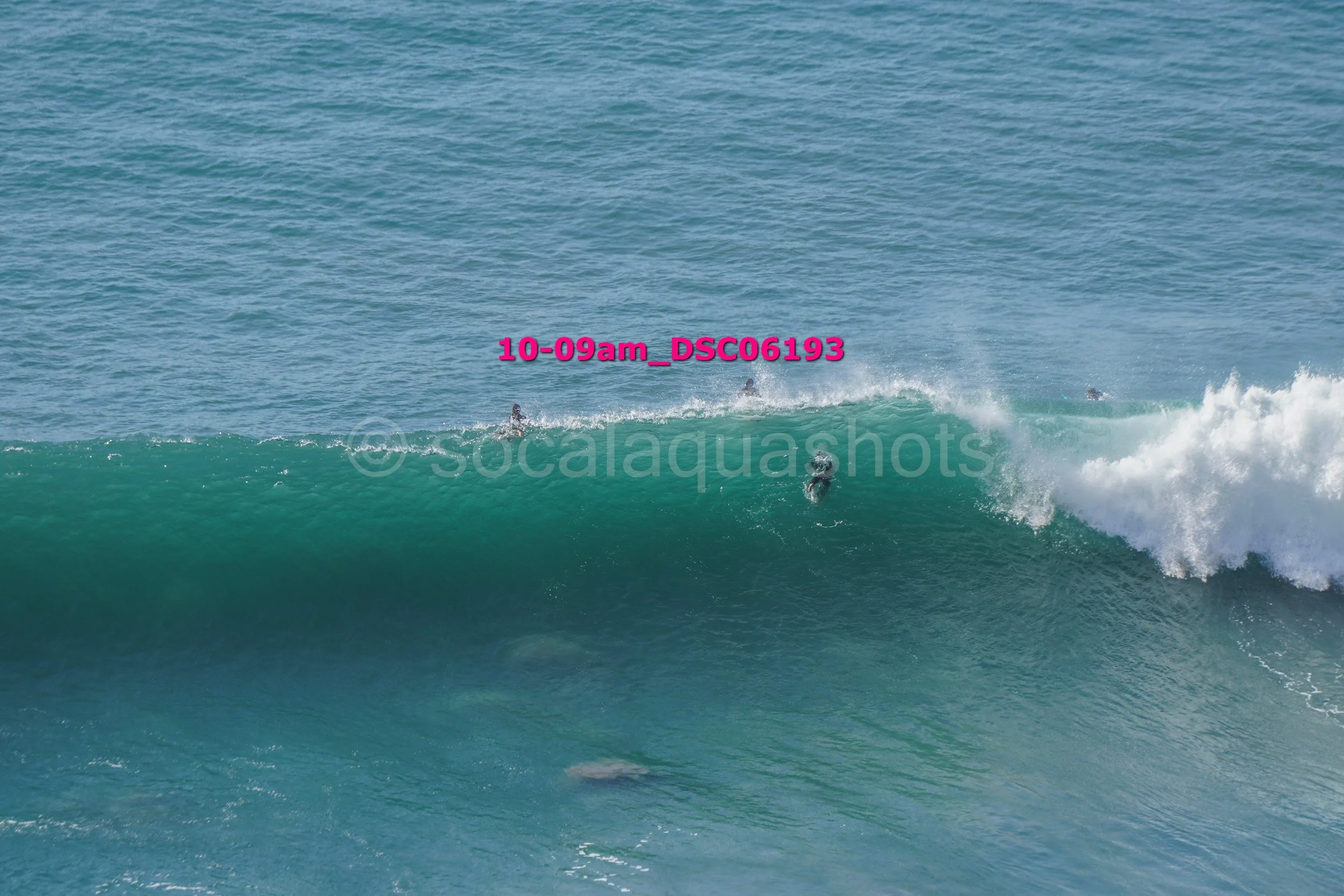 Group of surfers riding a large wave in the ocean.