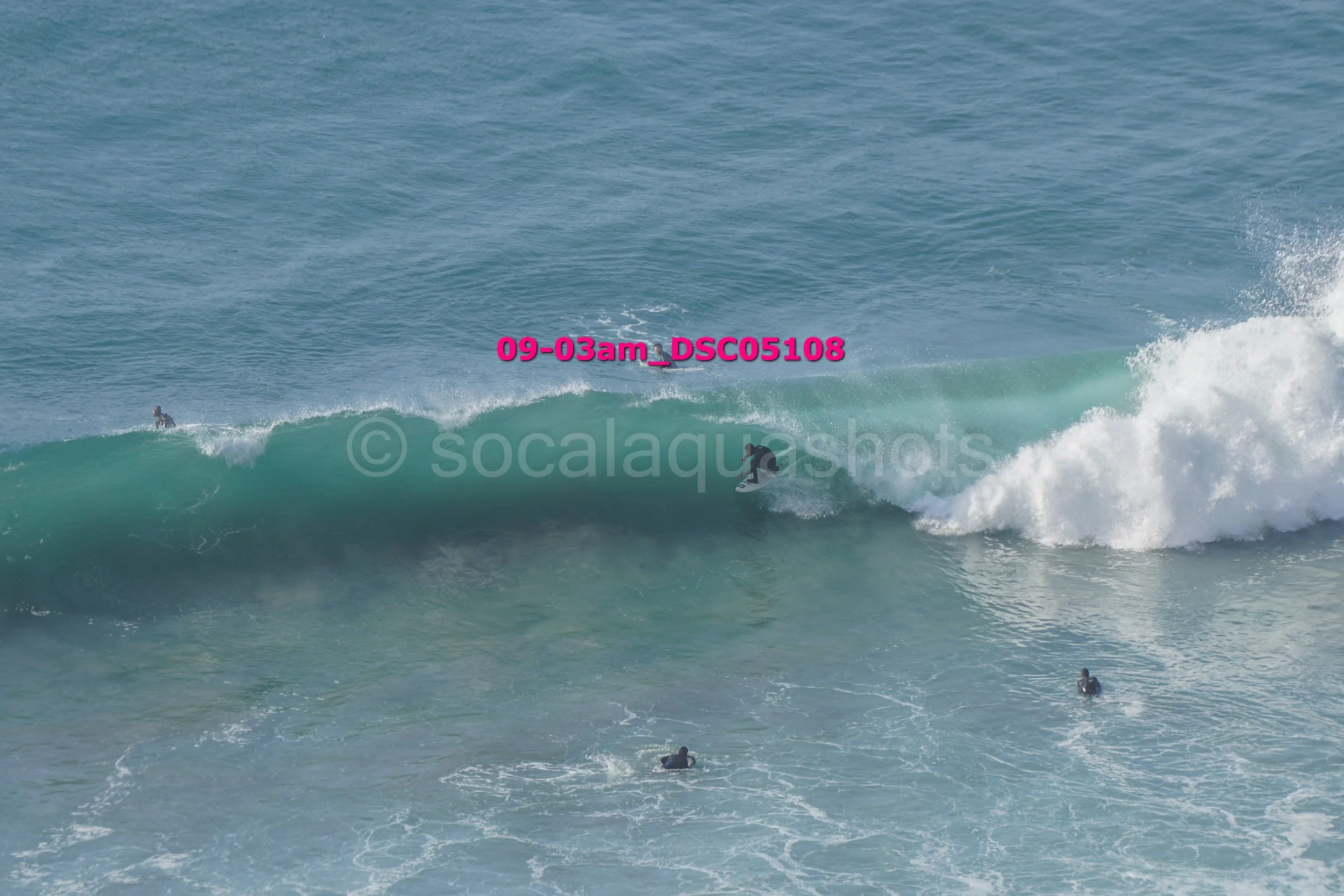 A surfer riding a wave in the ocean with other surfers in the water around them