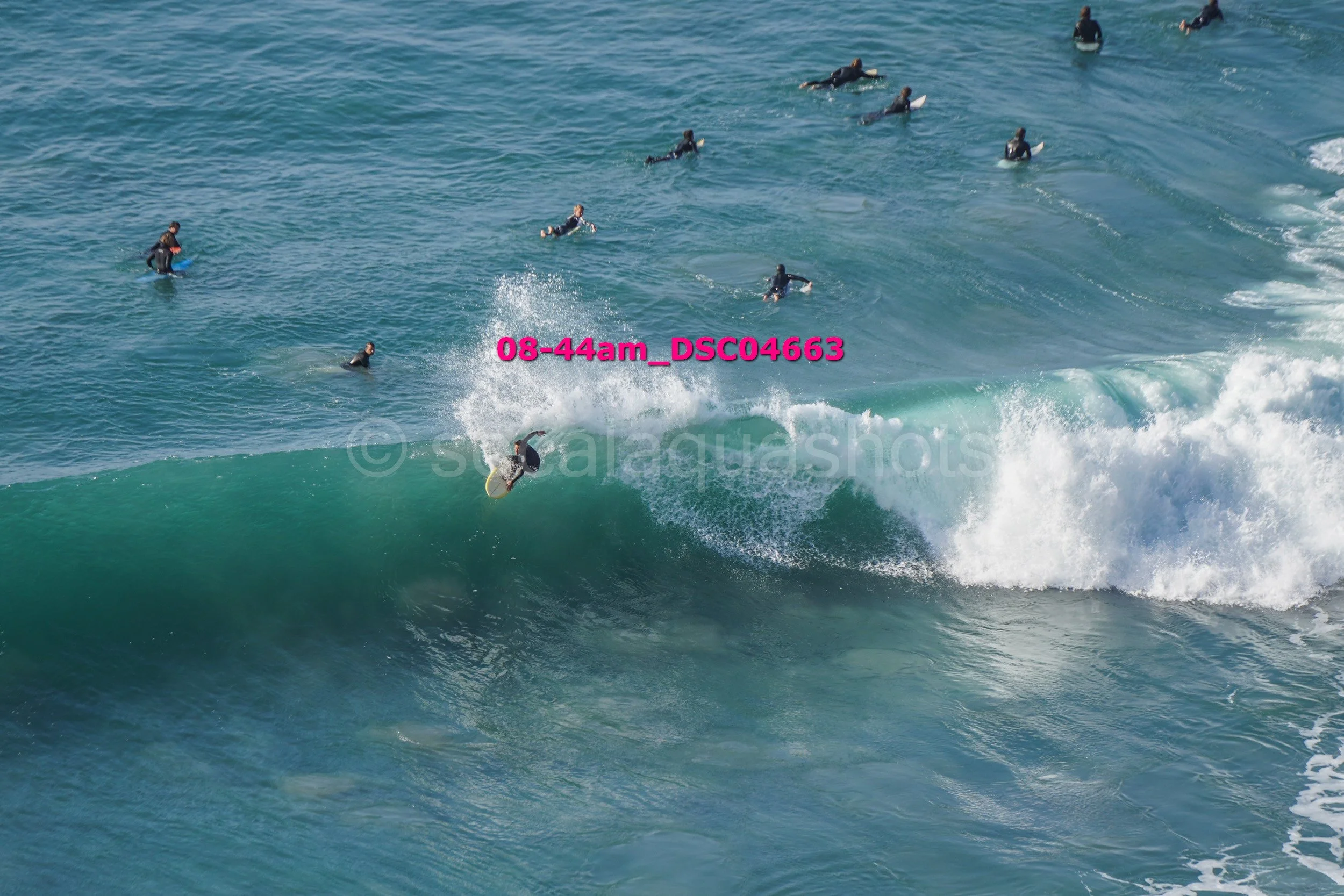 Surfer riding a wave with multiple people in the water watching