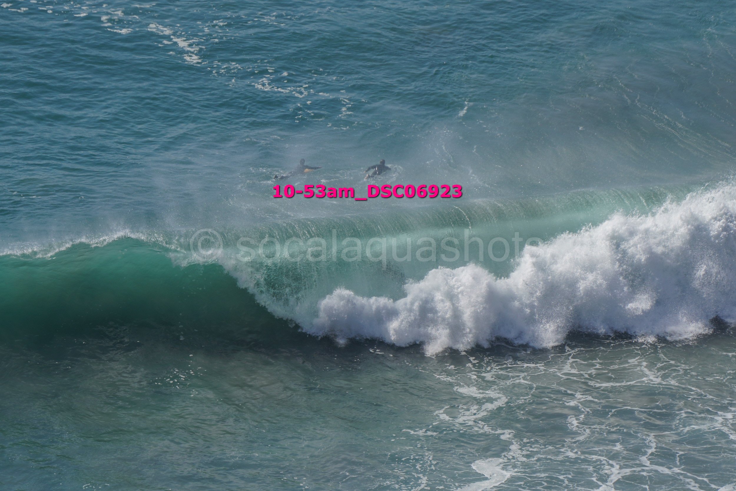 Two surfers riding a large ocean wave near the shore.
