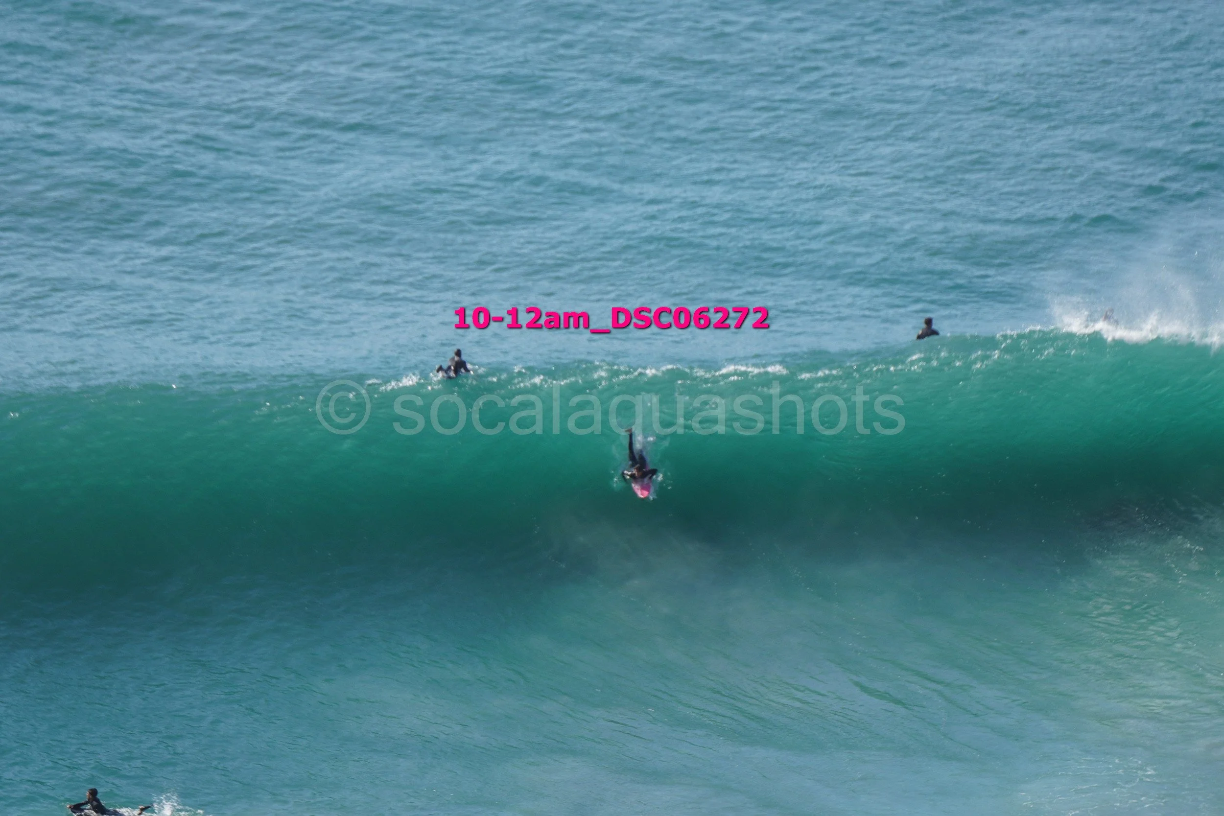Surfer falling off a wave while other surfers are in the water behind.
