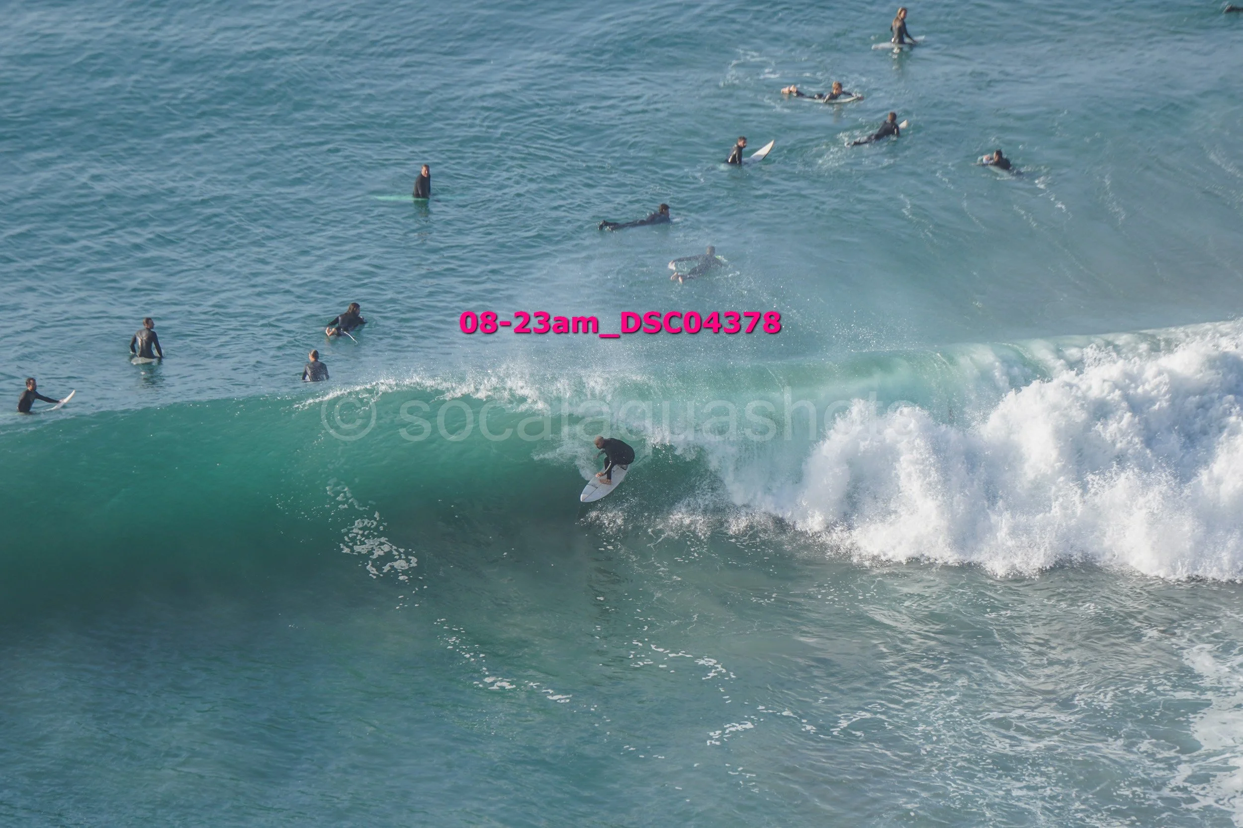 Surfer riding a wave with several people in the water watching.