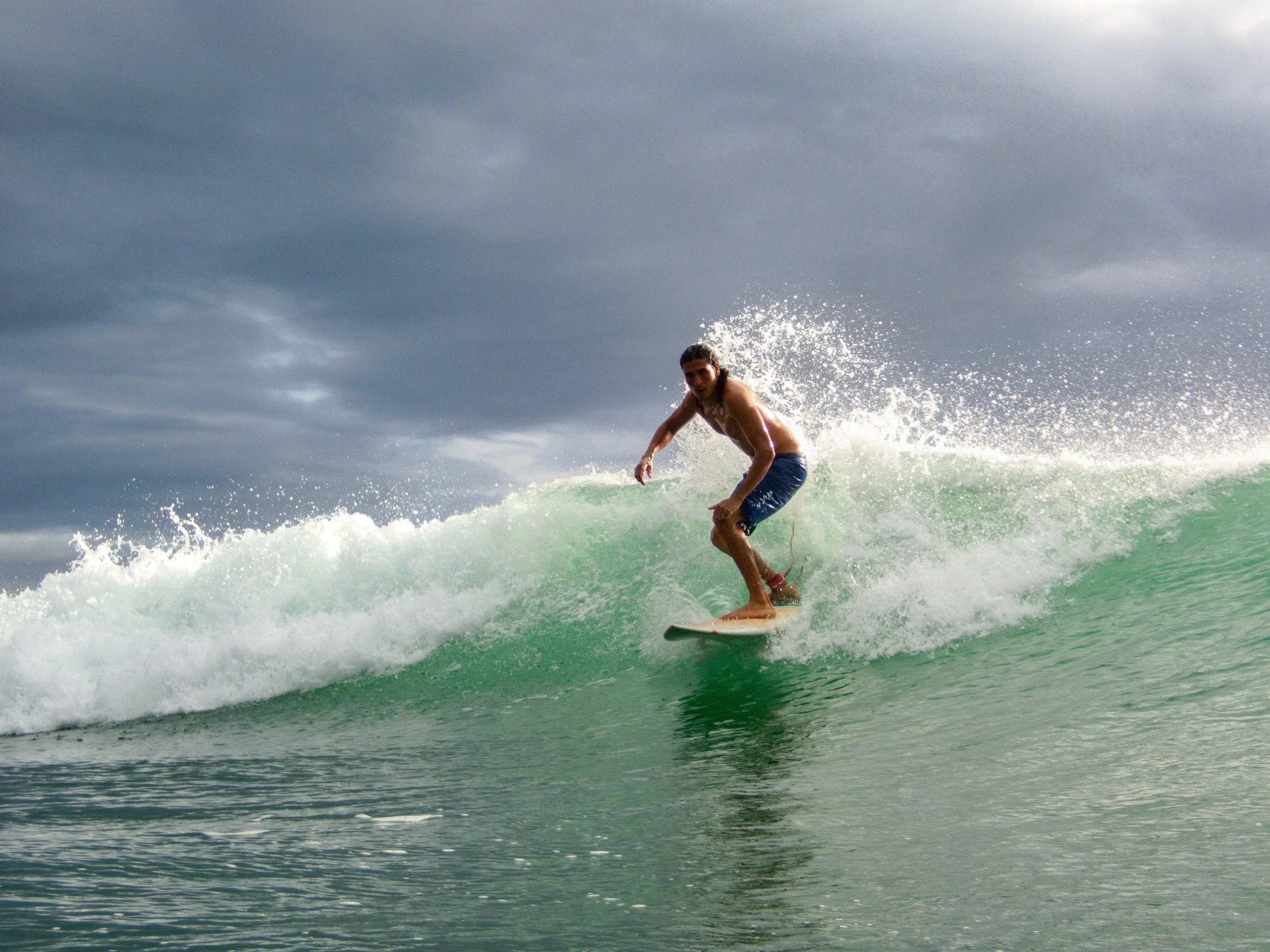 Surfer riding a wave under a cloudy sky